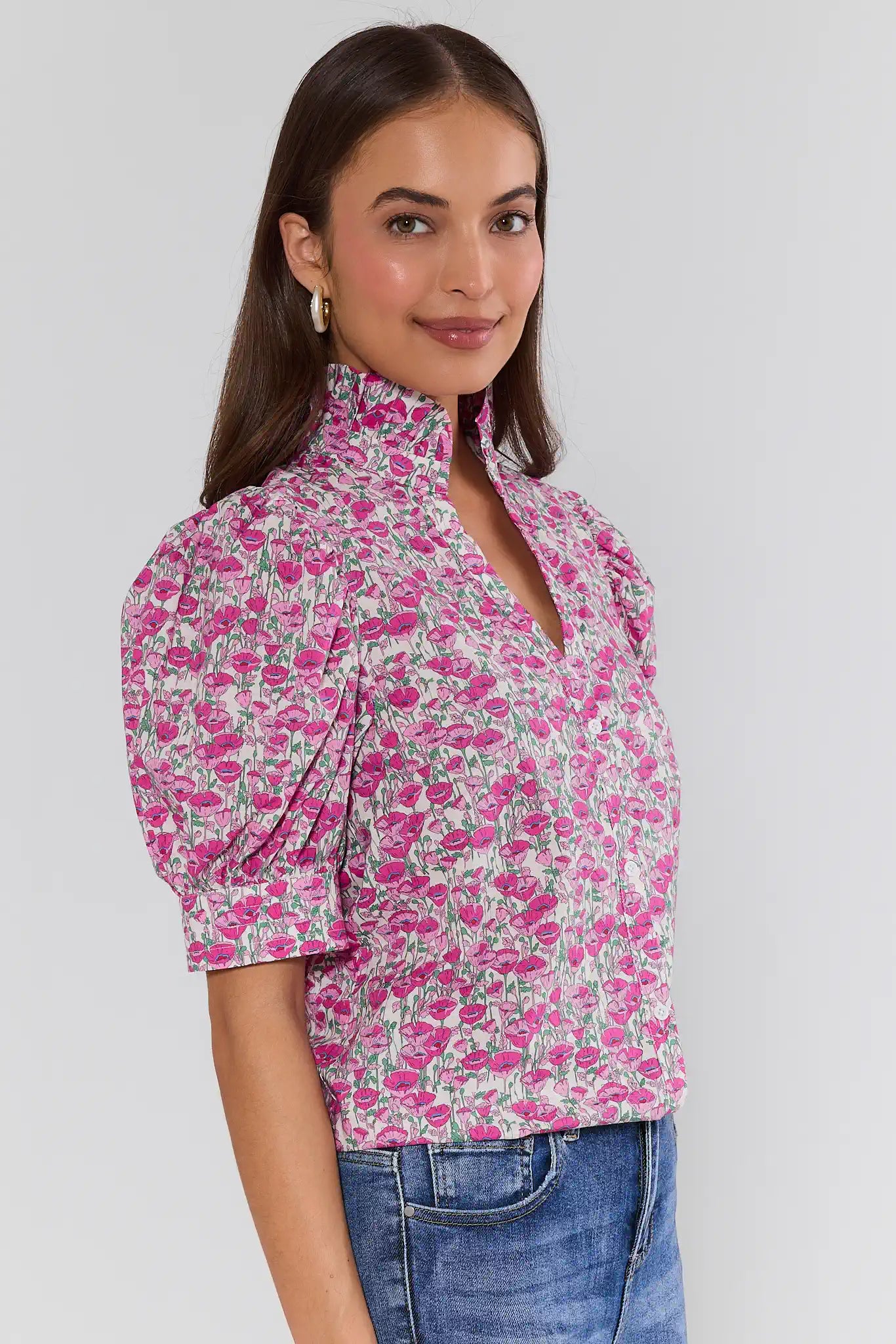 Woman wearing a pink floral blouse with blue jeans on a white background