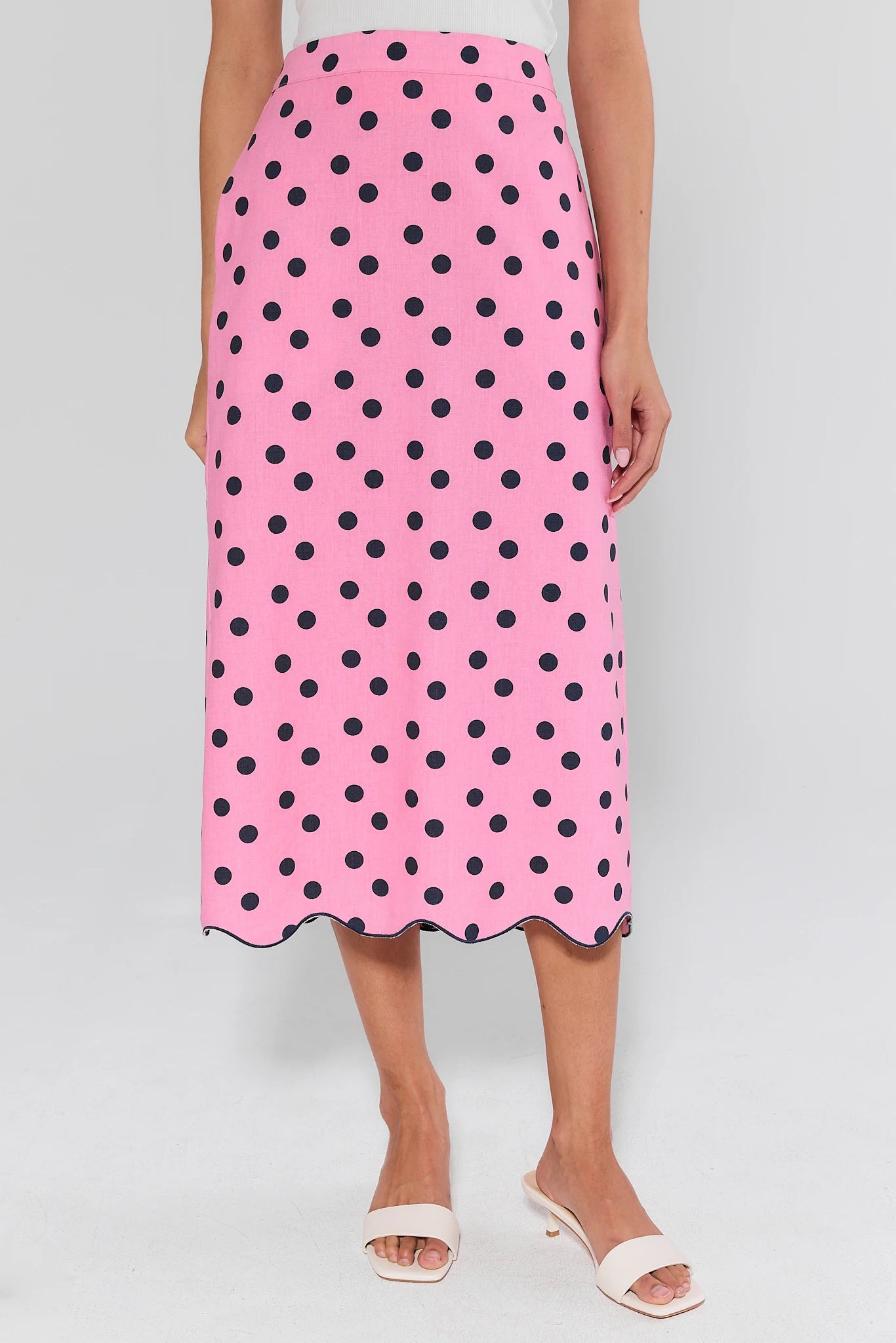 Pink skirt with black polka dots worn by a person on a white background