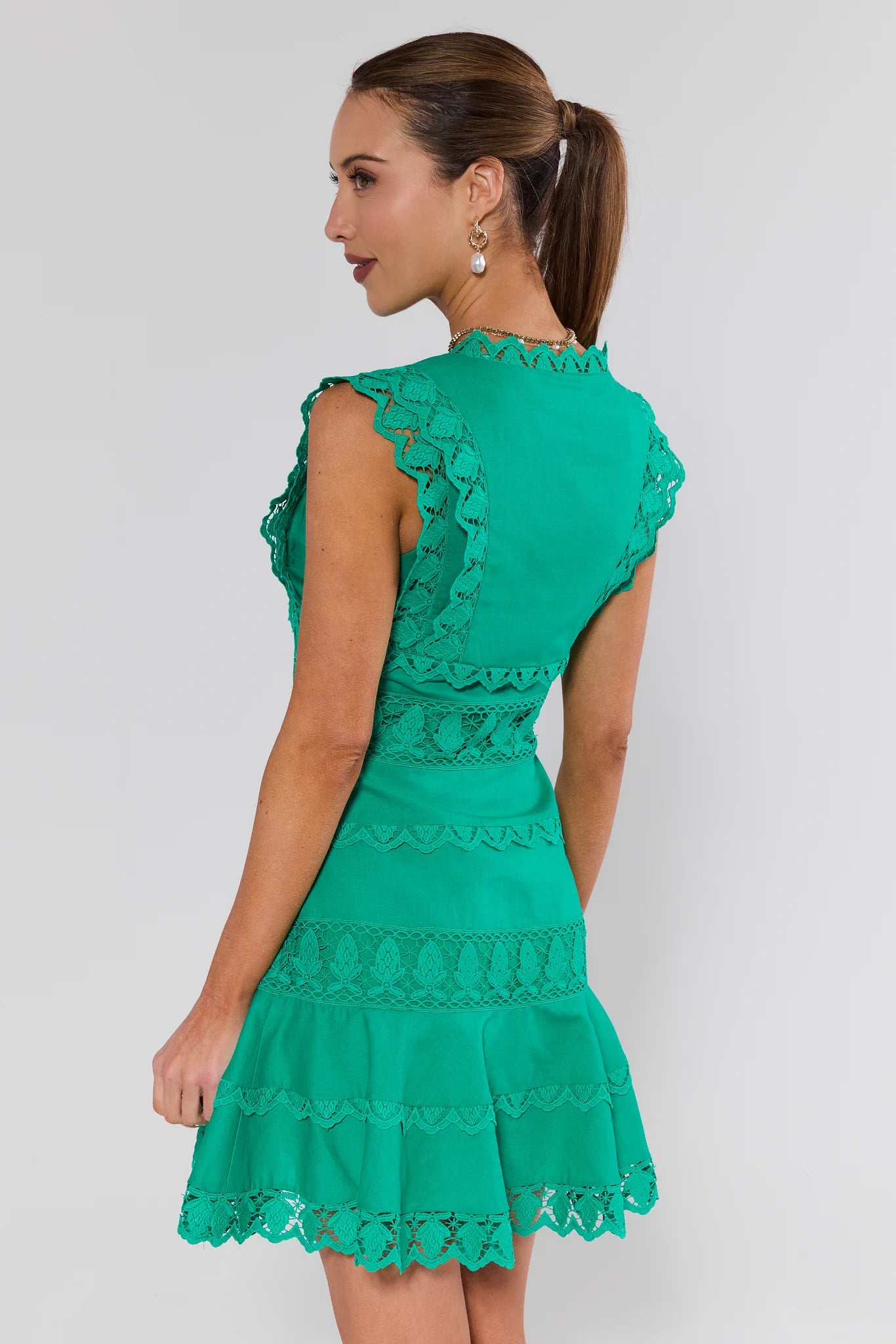 Woman wearing a green lace dress against a white background