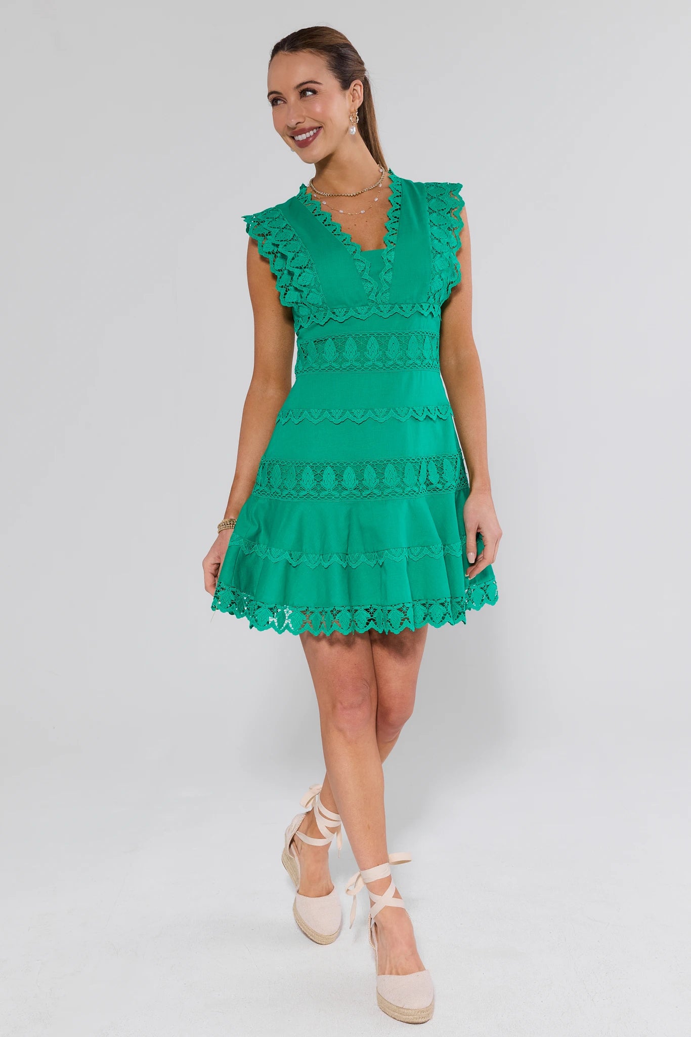 Woman wearing a green dress with ruffled details on a white background
