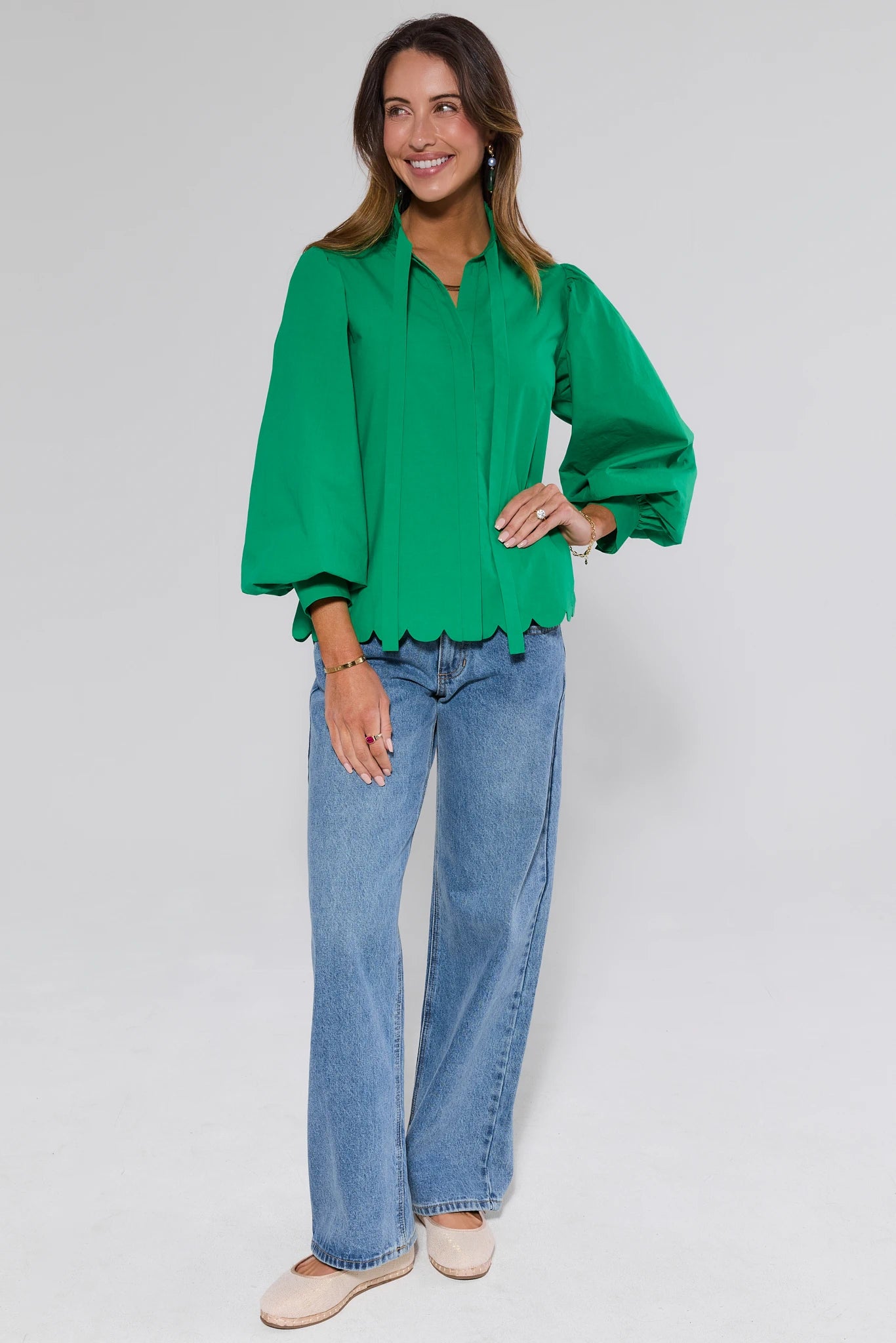 View 2: Woman wearing a green blouse and blue jeans on a white background