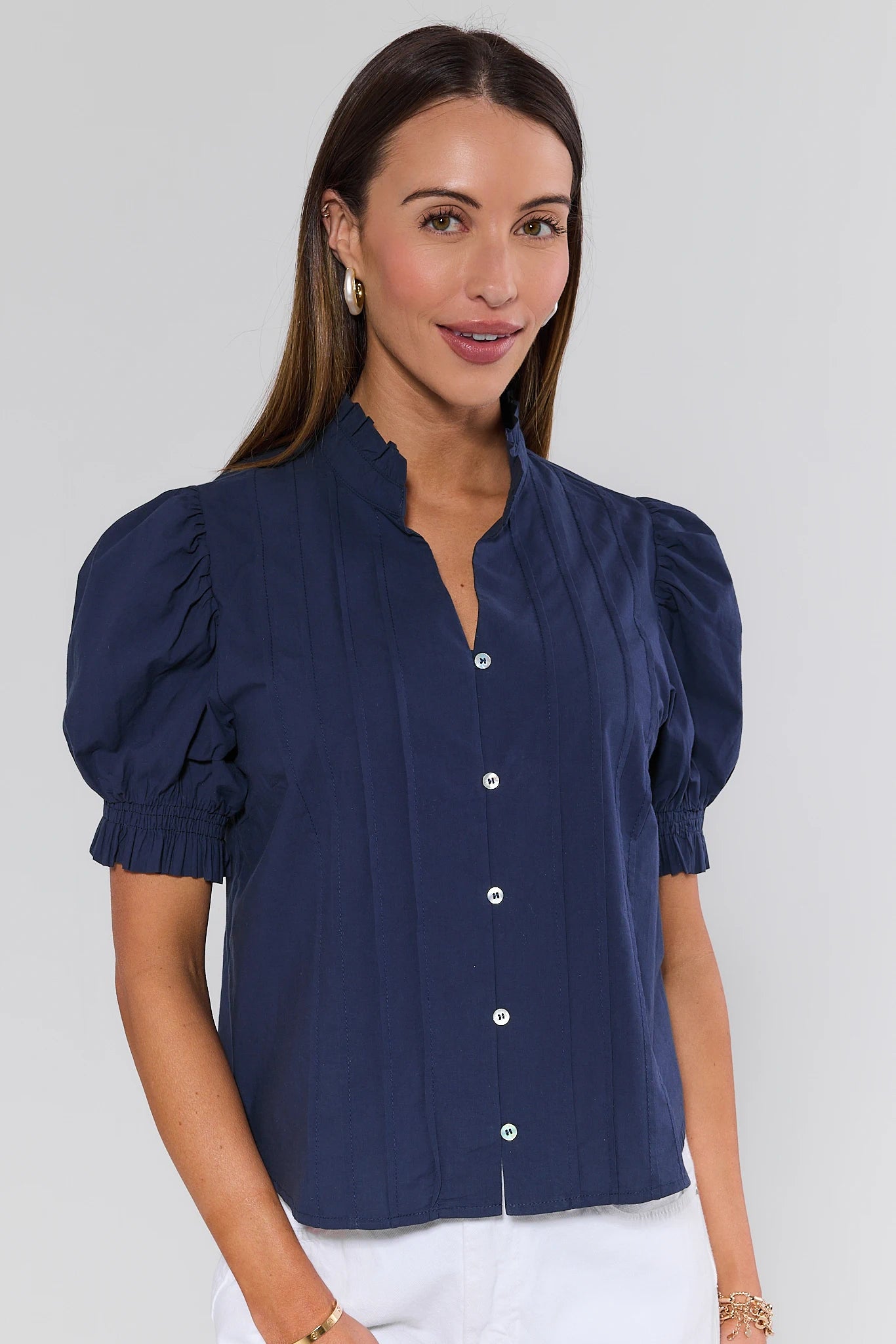 Woman wearing a navy blue blouse with puffed sleeves against a plain background