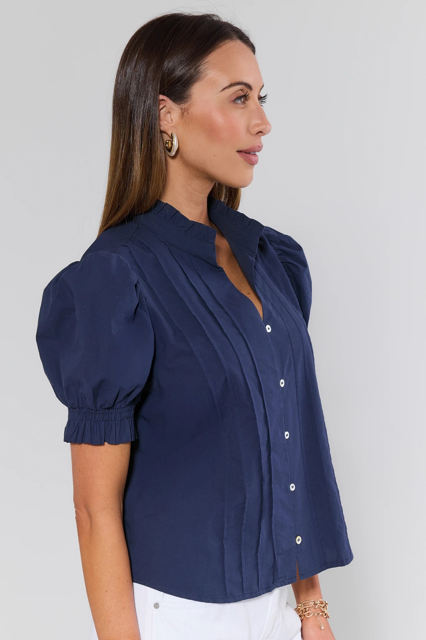 Woman wearing a navy blue blouse with puffed sleeves against a plain background