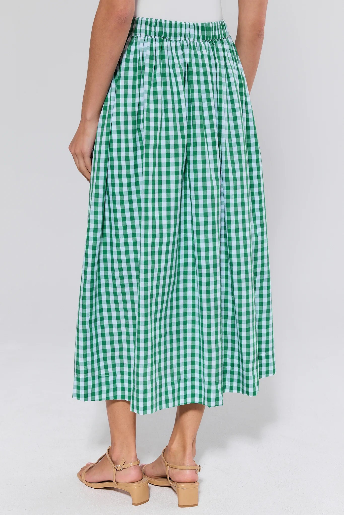 Green and white checkered skirt worn by a woman on a plain background