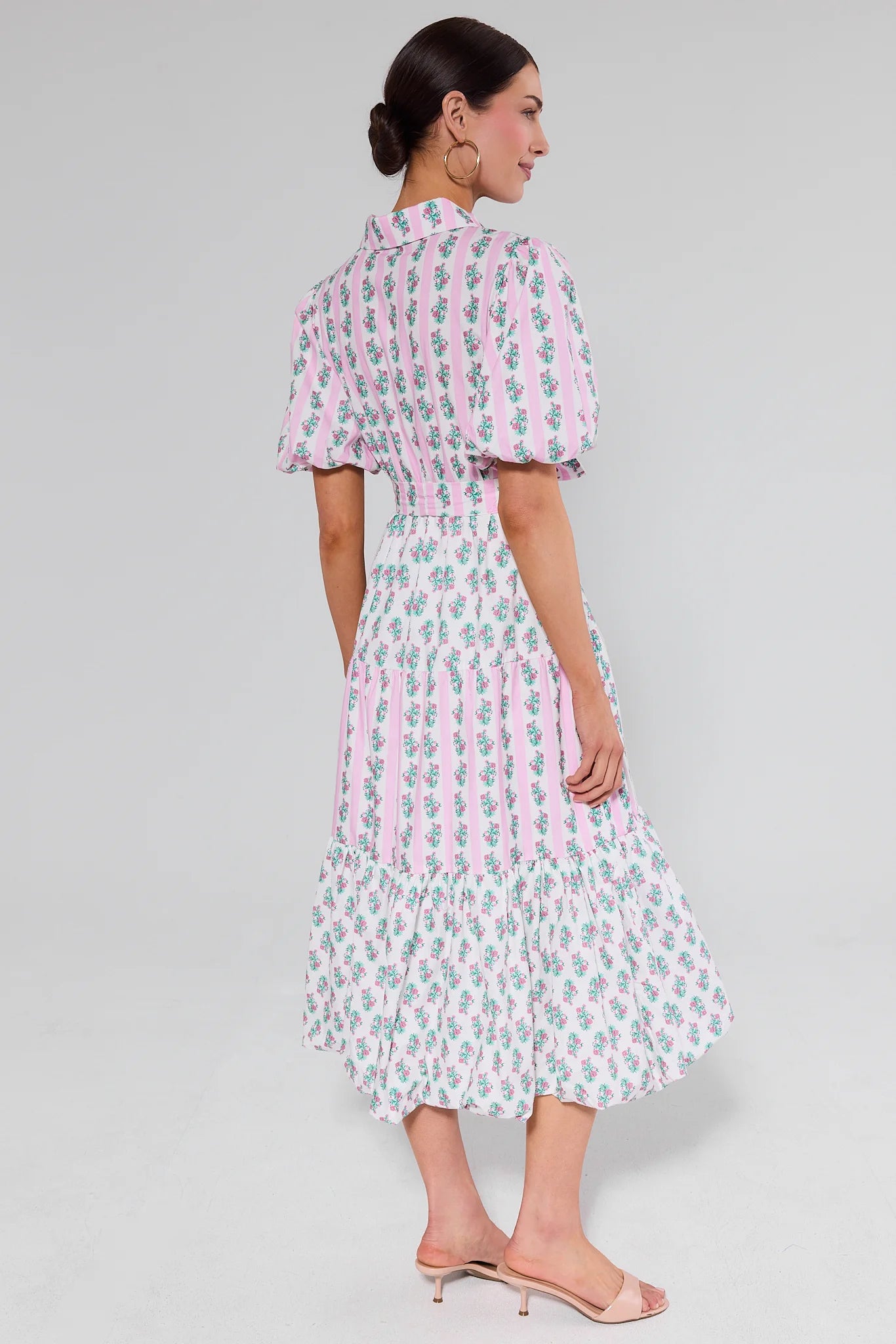 Woman wearing a pink and white patterned dress standing on a gray background