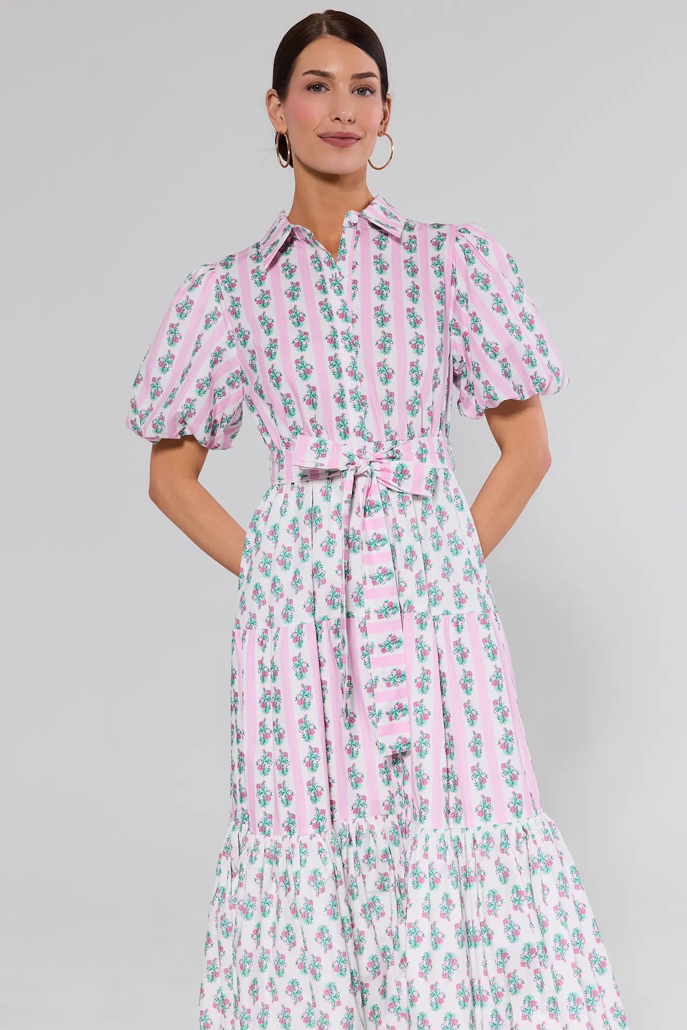 Woman wearing a pink and white floral dress on a gray background