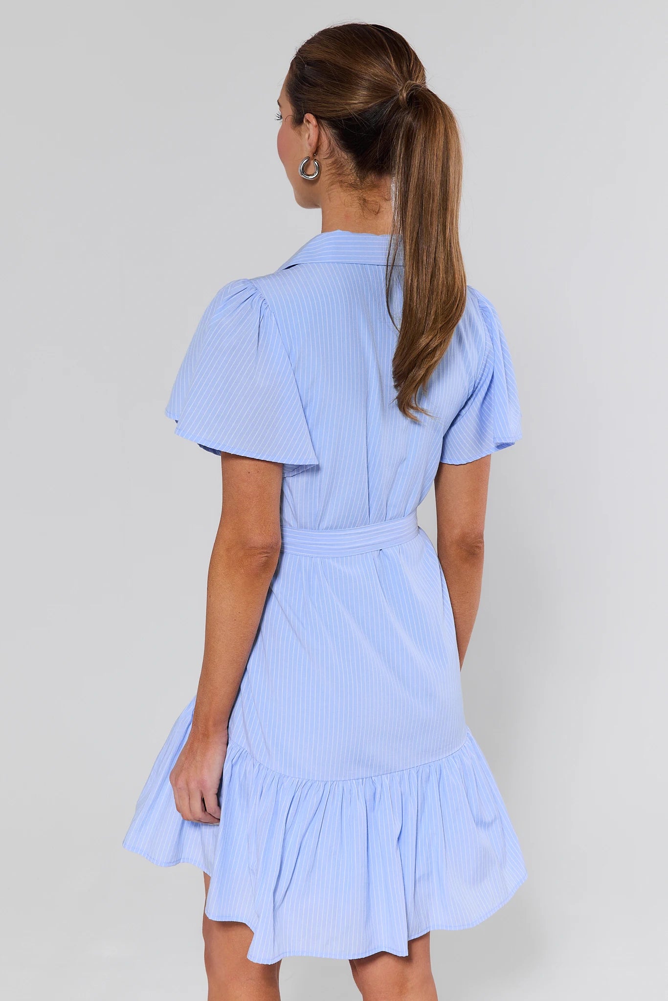 Woman wearing a light blue dress with a plain background