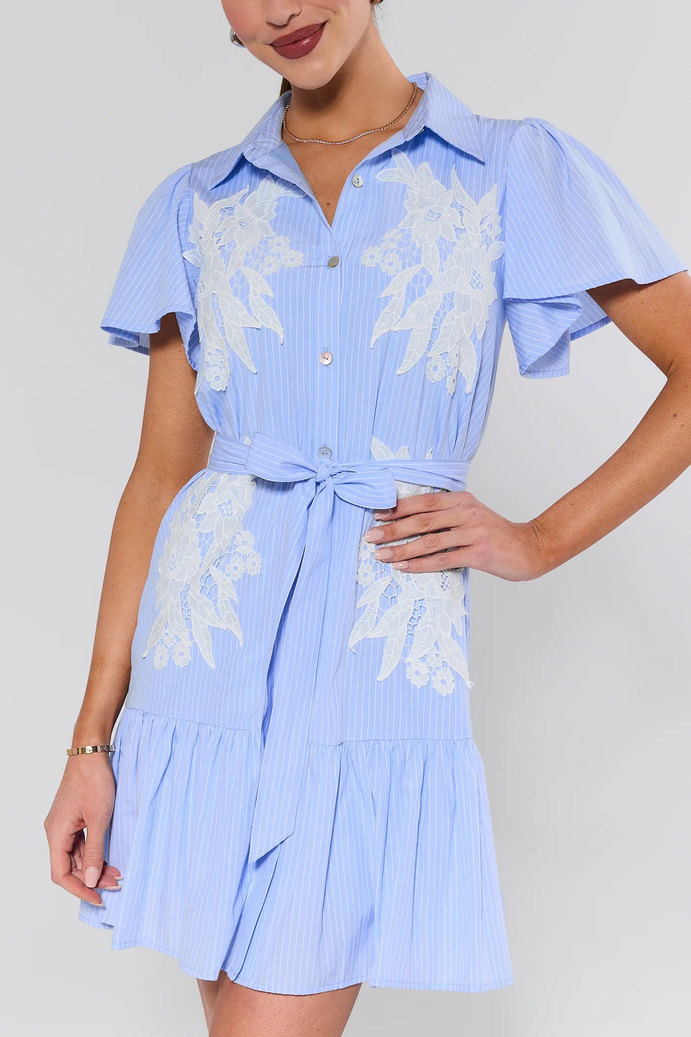 Woman wearing a blue dress with white floral patterns on a plain background