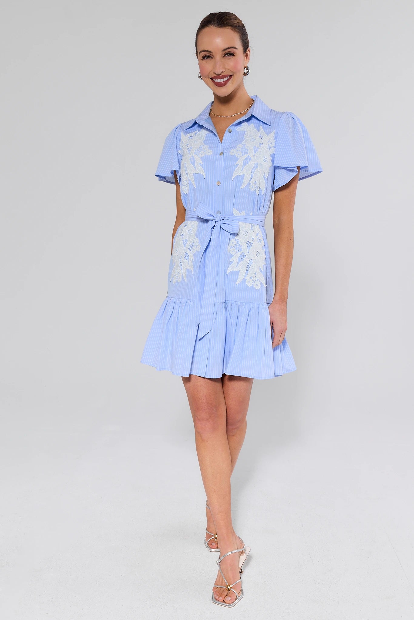 Woman wearing a light blue dress with floral patterns on a white background