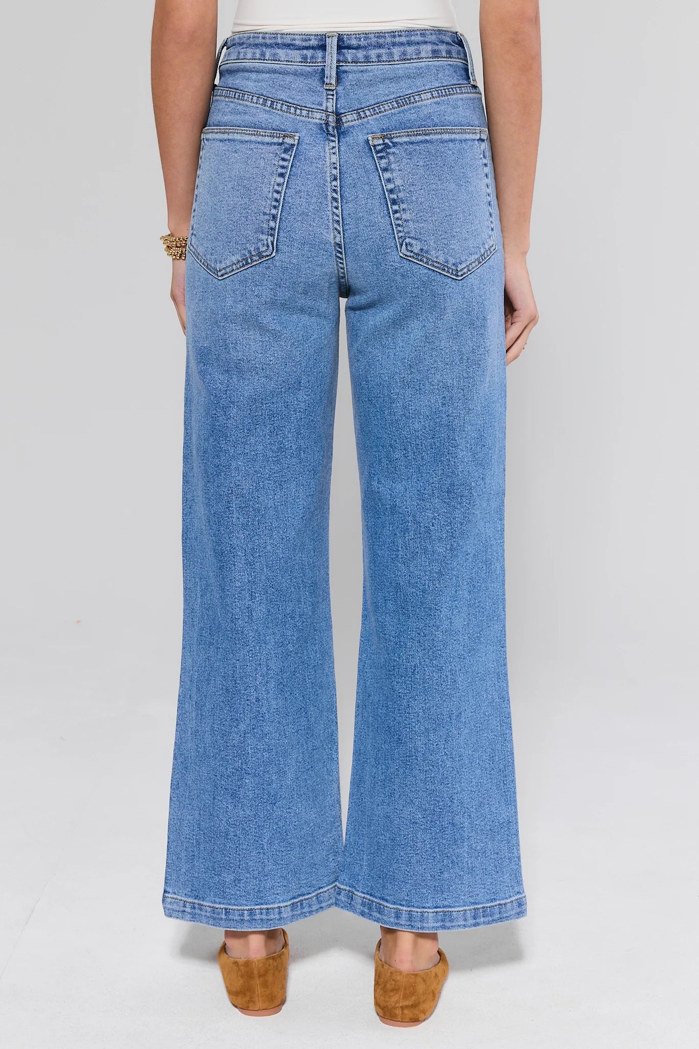 Blue jeans worn by a person on a white background