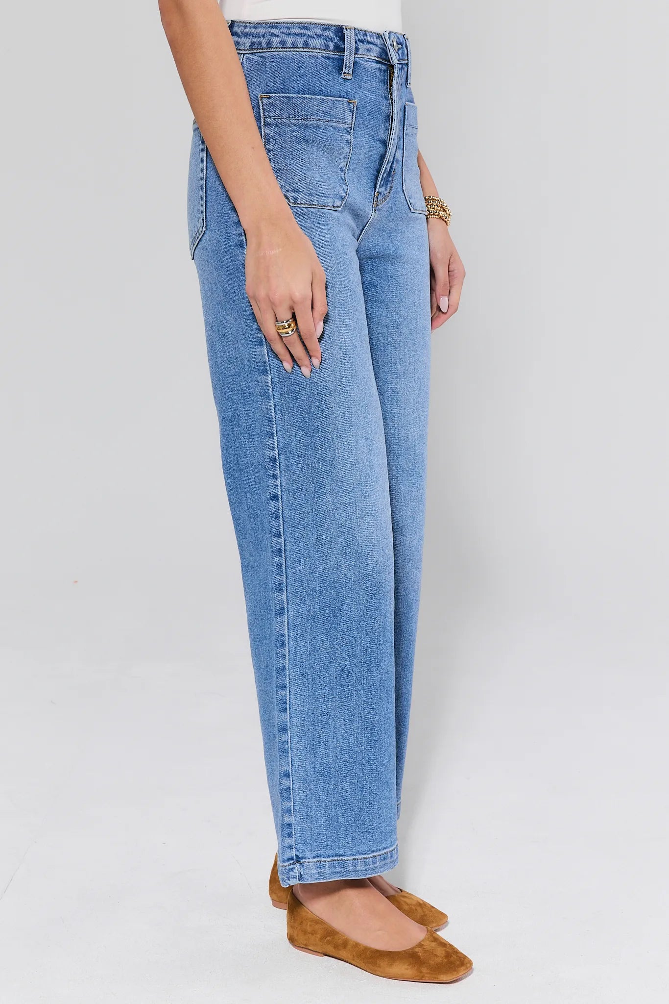 Person wearing blue jeans on a plain background