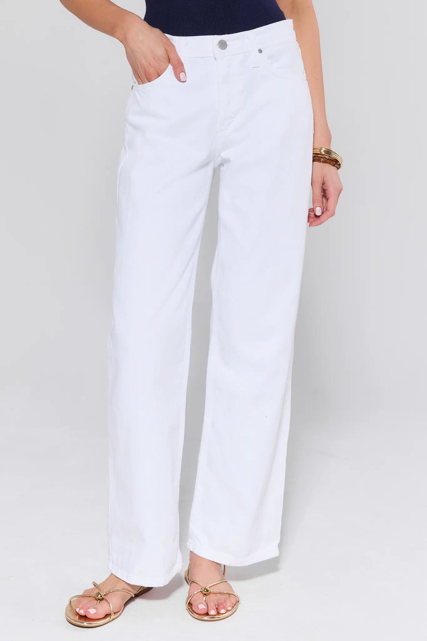 Person wearing white jeans on a plain background