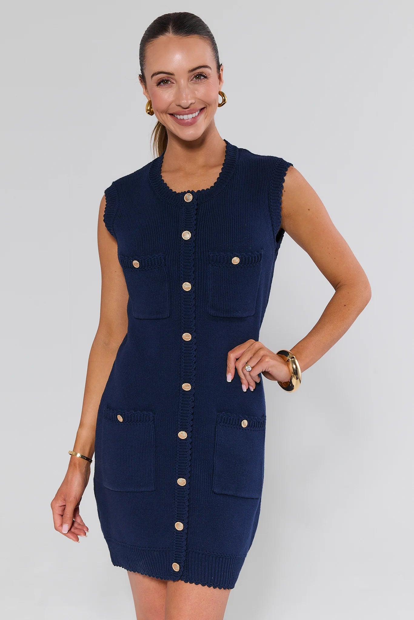 Woman wearing a navy blue dress with beige buttons on a white background