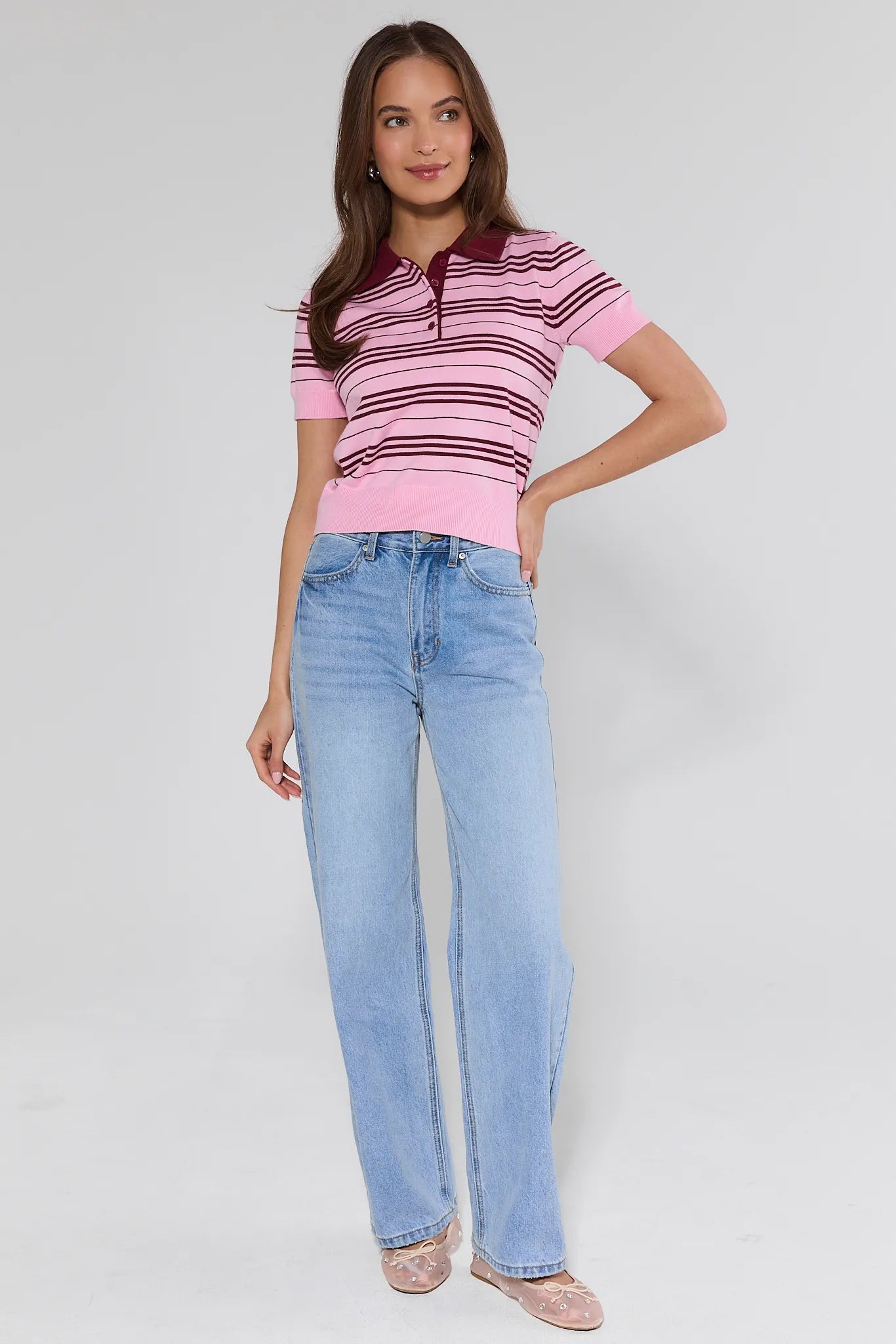 woman wearing pinks striped tee and light wash jeans with mesh flats on white background