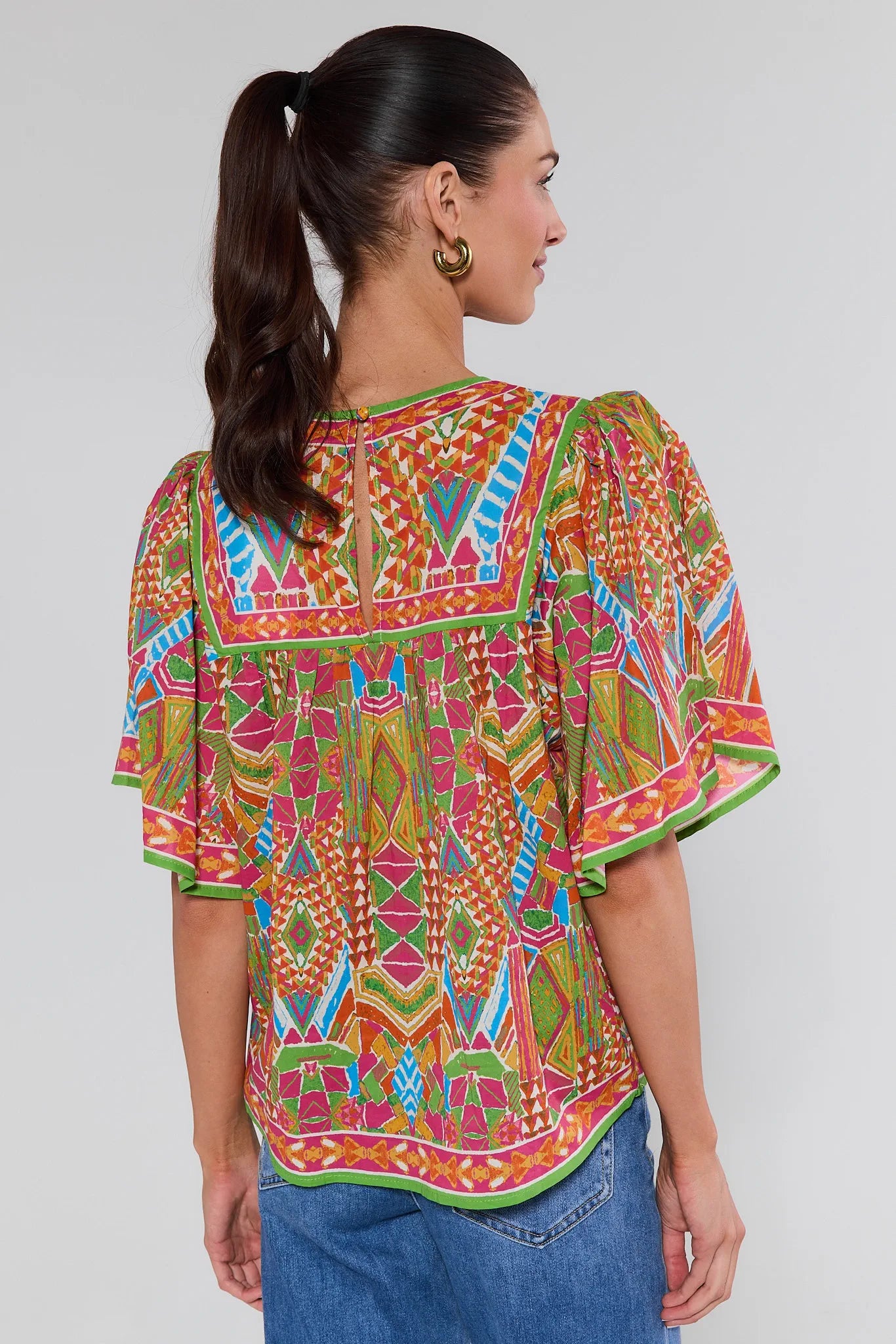 Woman wearing a colorful patterned top on a white background