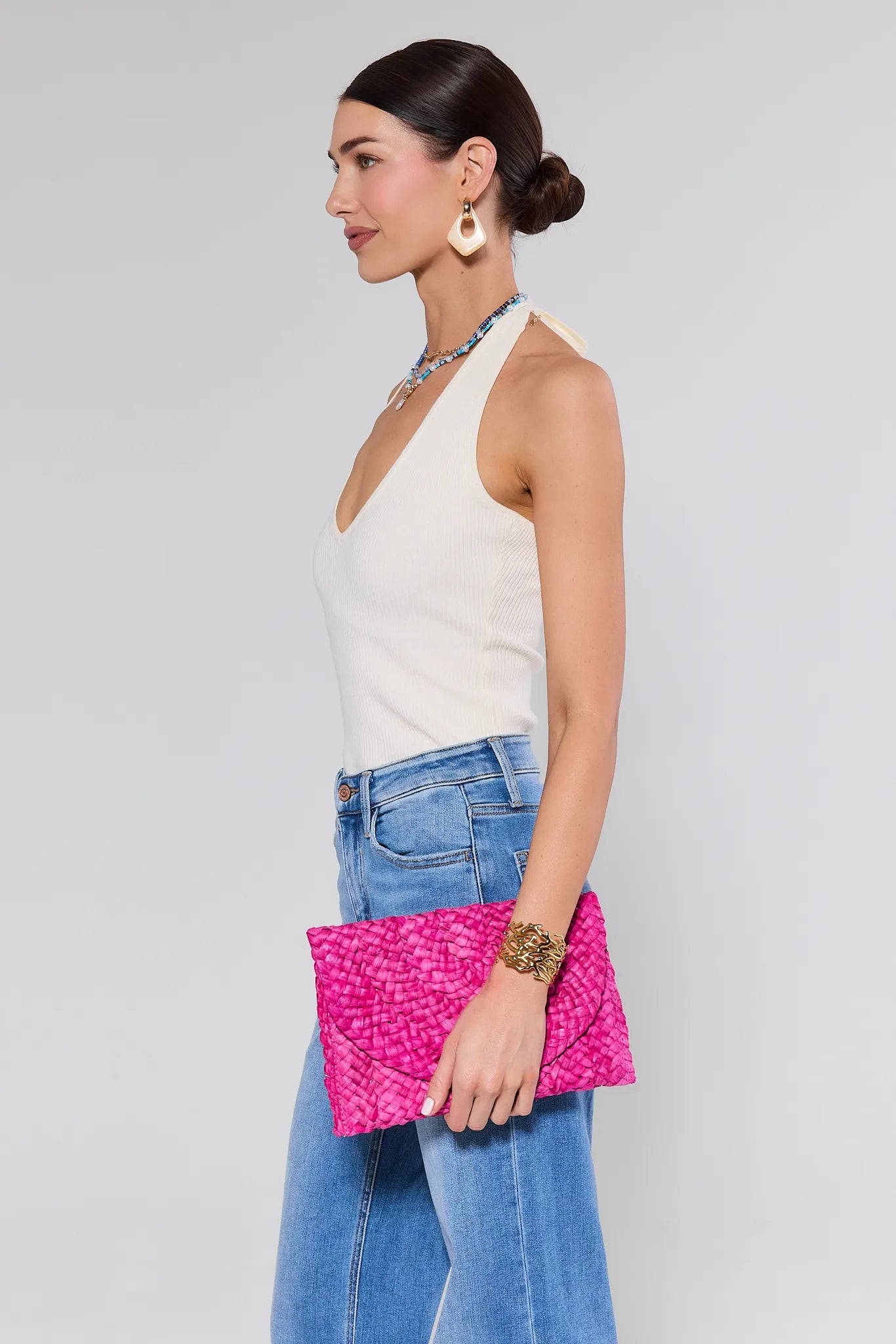 Woman holding a pink clutch against a plain background