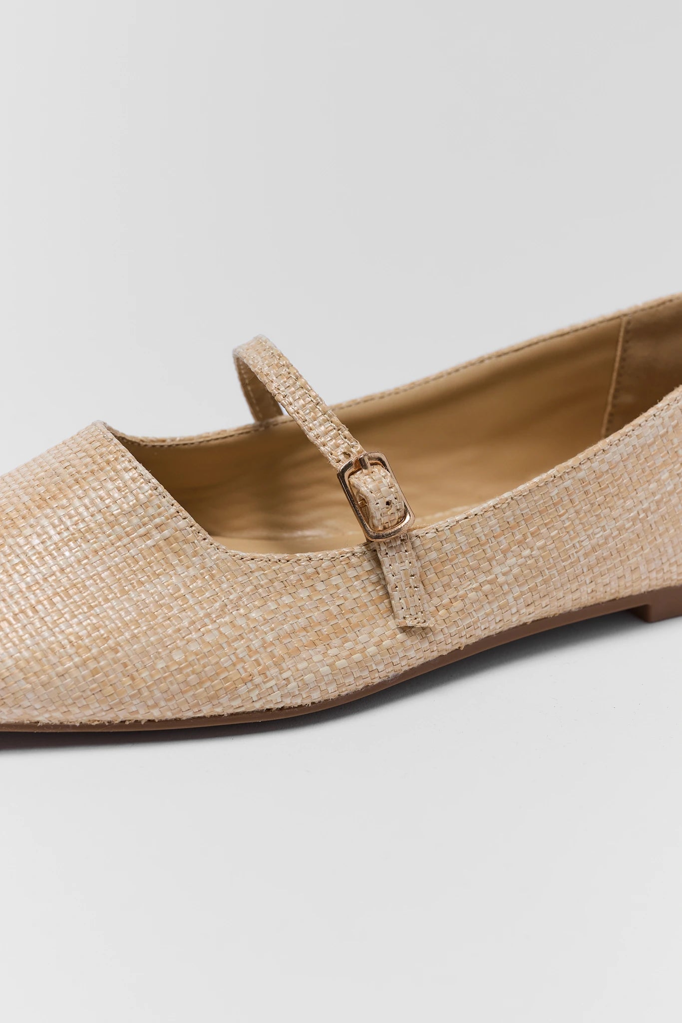 Beige flat shoe with a strap on a gray background