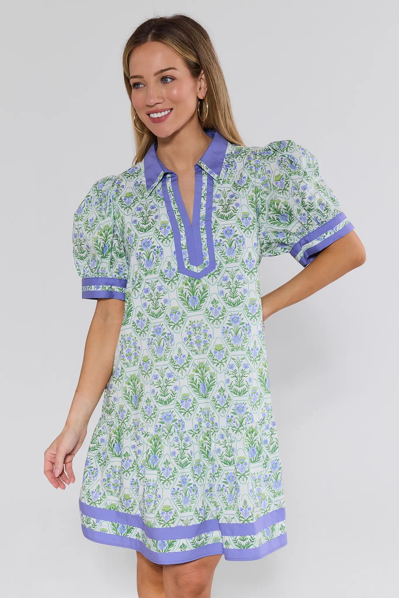 Woman wearing a floral dress with purple accents on a white background