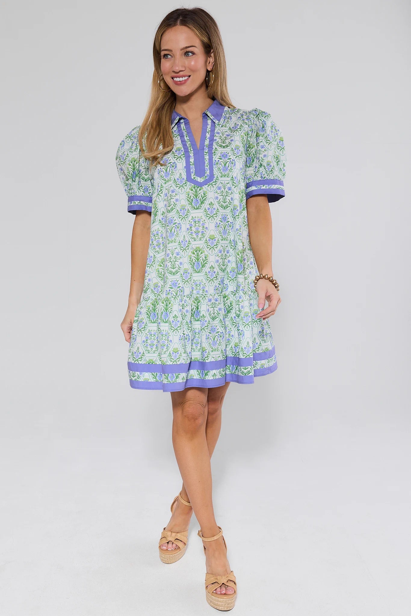 Woman wearing a floral dress with purple accents on a white background