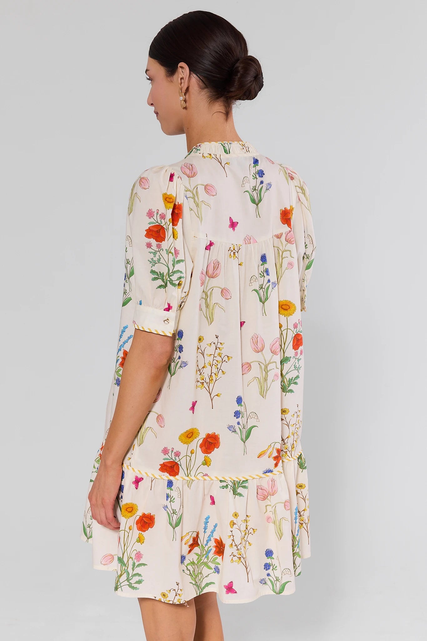 Woman standing wearing a floral dress with a plain background