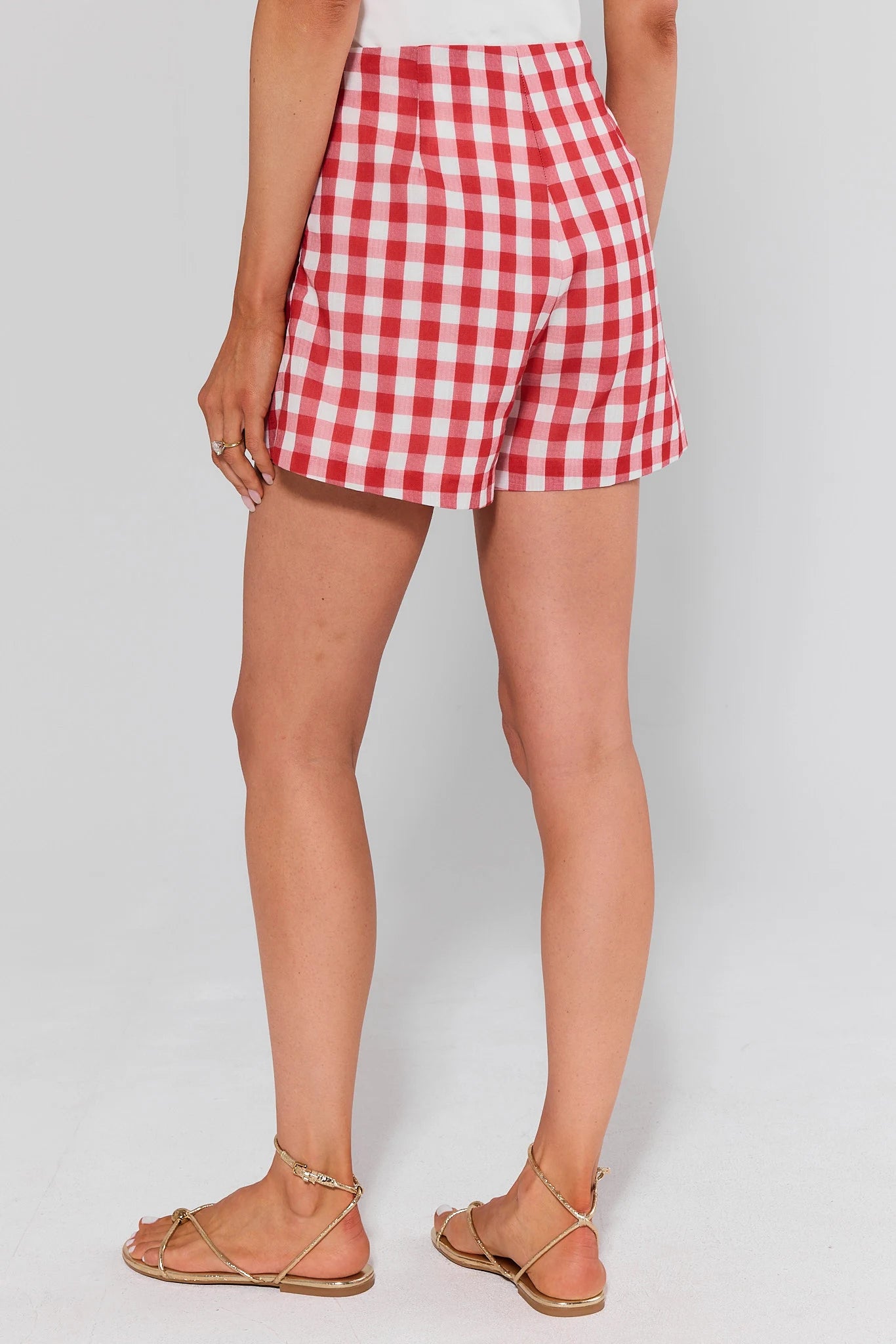 standing Red and white checkered shorts worn by a person on a plain background