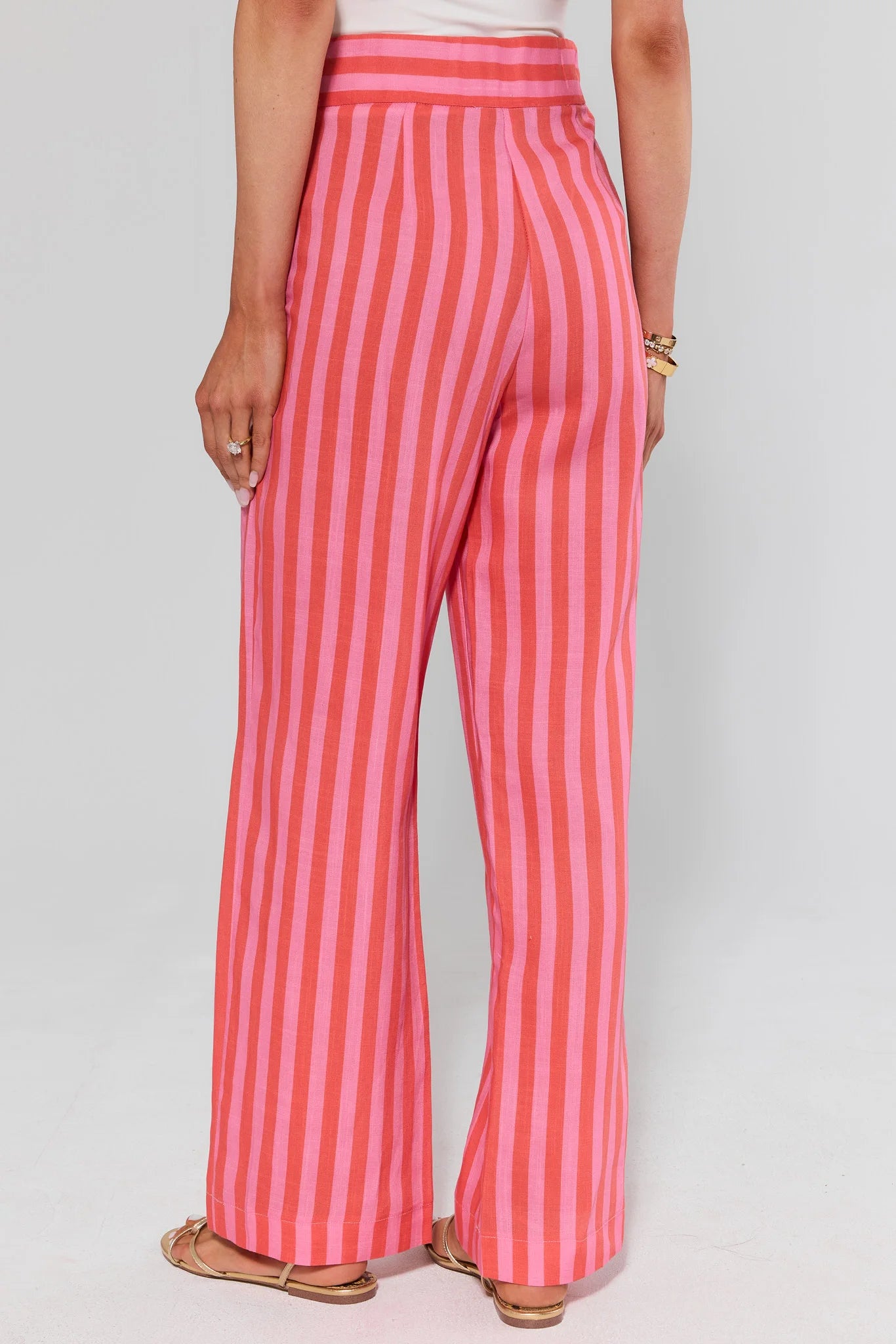 Person standing wearing pink and red striped pants on a plain background