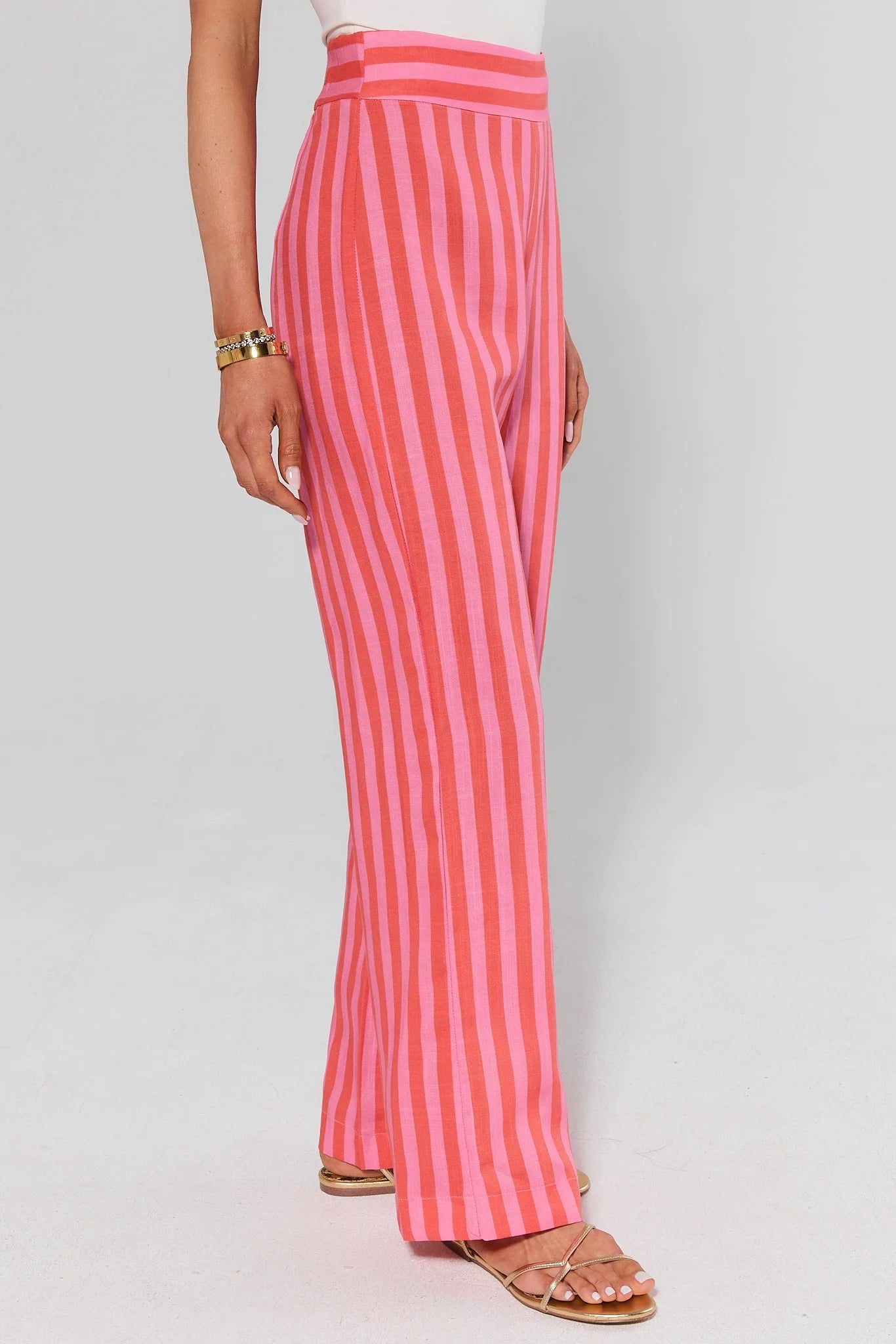 side shot Pink and red striped pants worn by a person on a light gray background