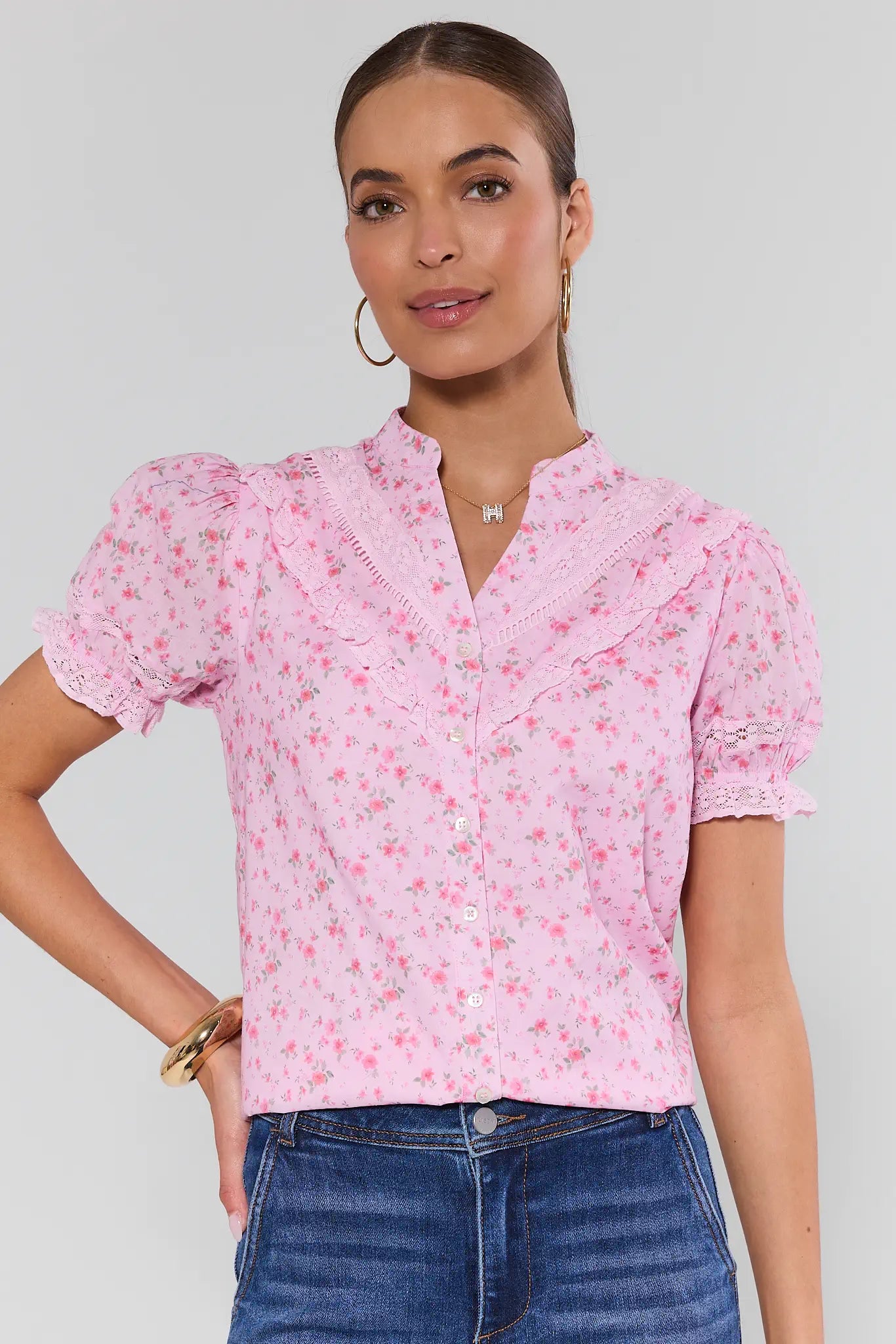 Woman wearing a pink floral blouse with blue jeans on a light gray background