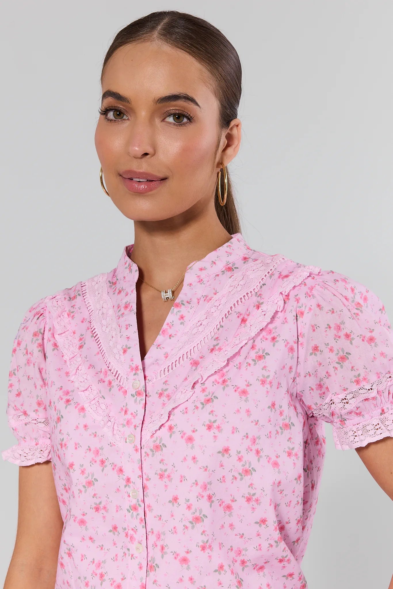 Woman wearing a pink floral blouse against a plain background