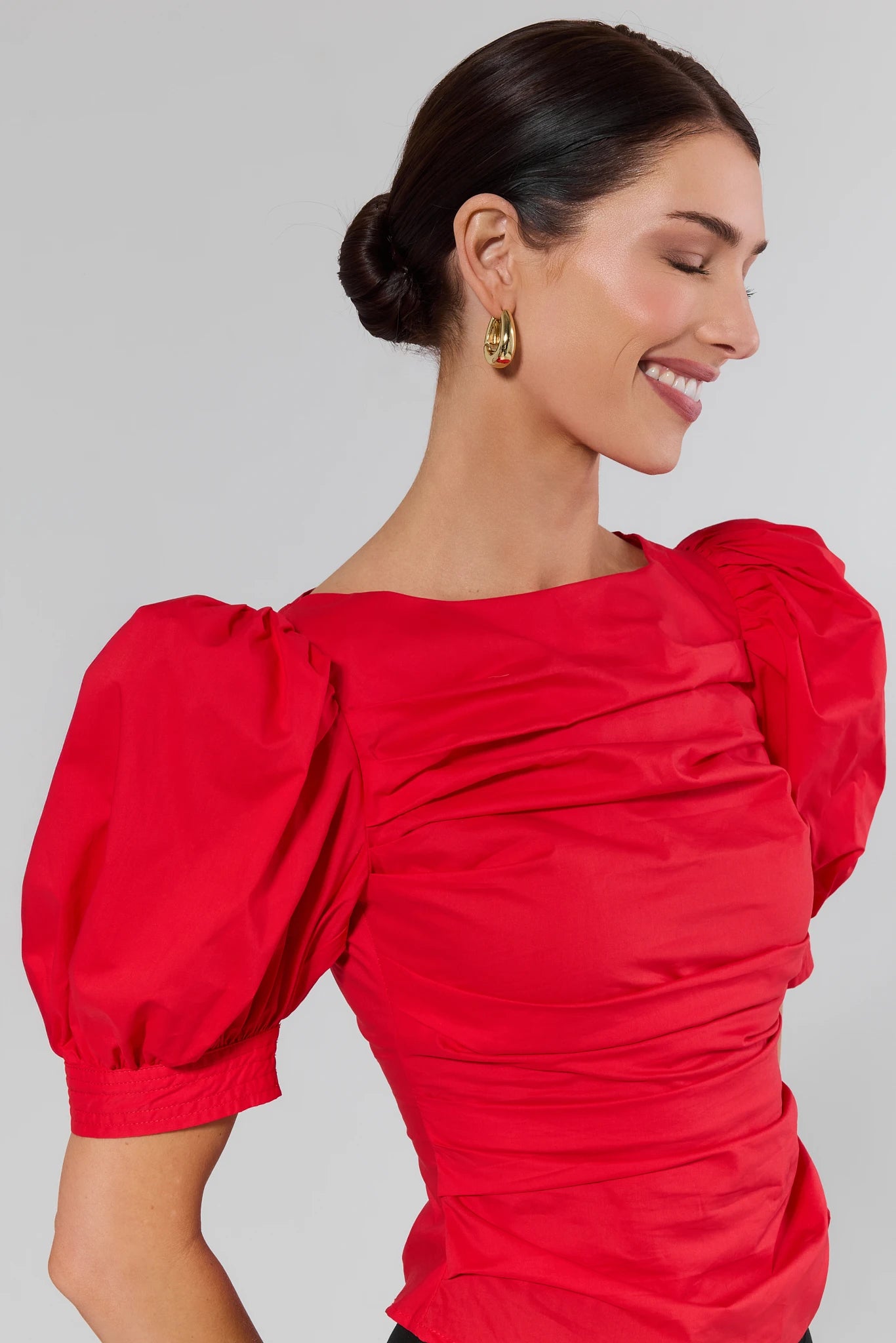 Woman wearing a red dress with puffed sleeves against a background