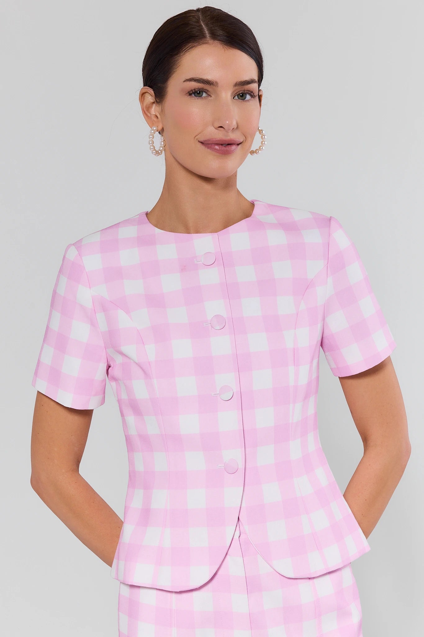 Woman wearing a pink checkered outfit against a gray background