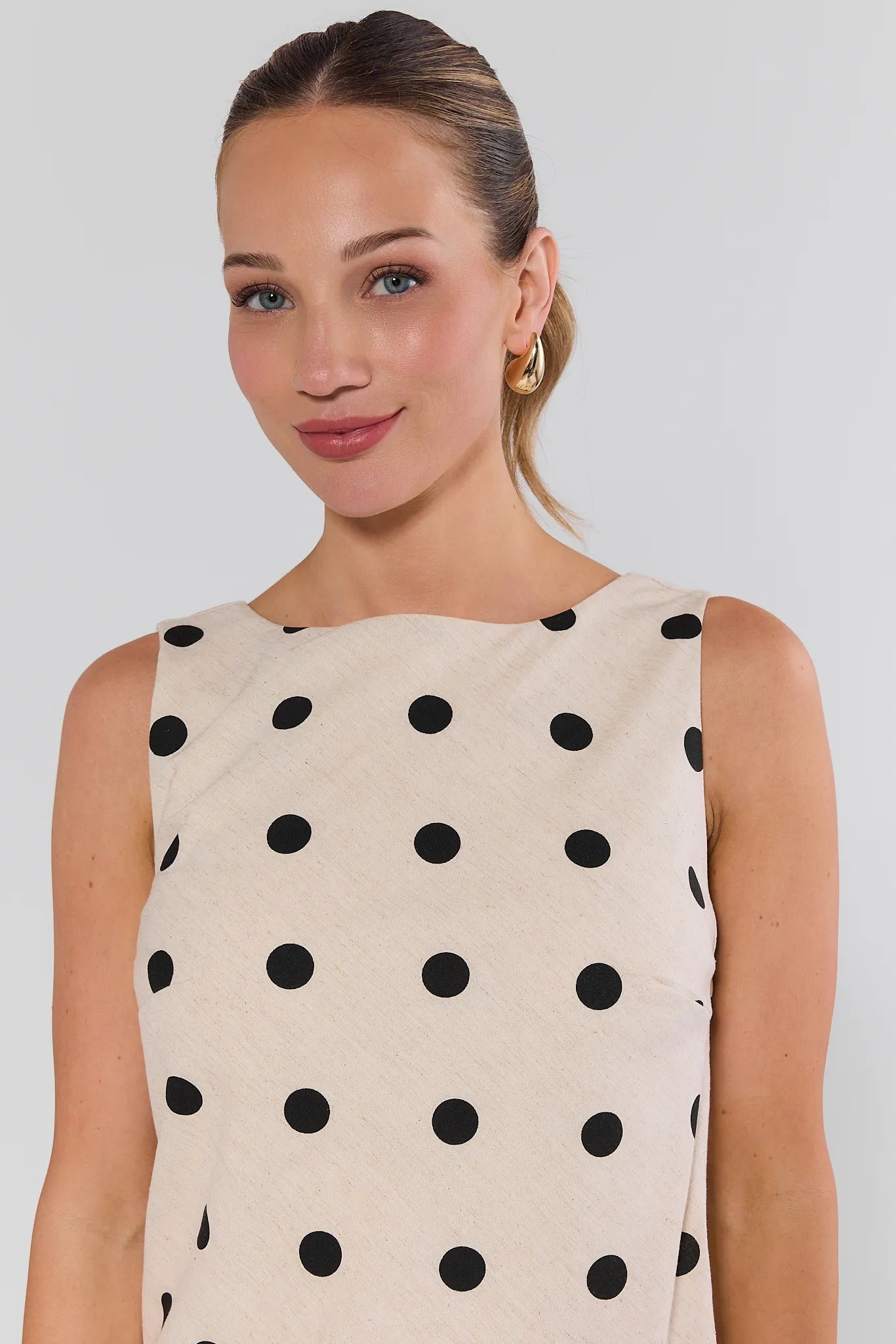 Woman wearing a beige dress with black polka dots on a background