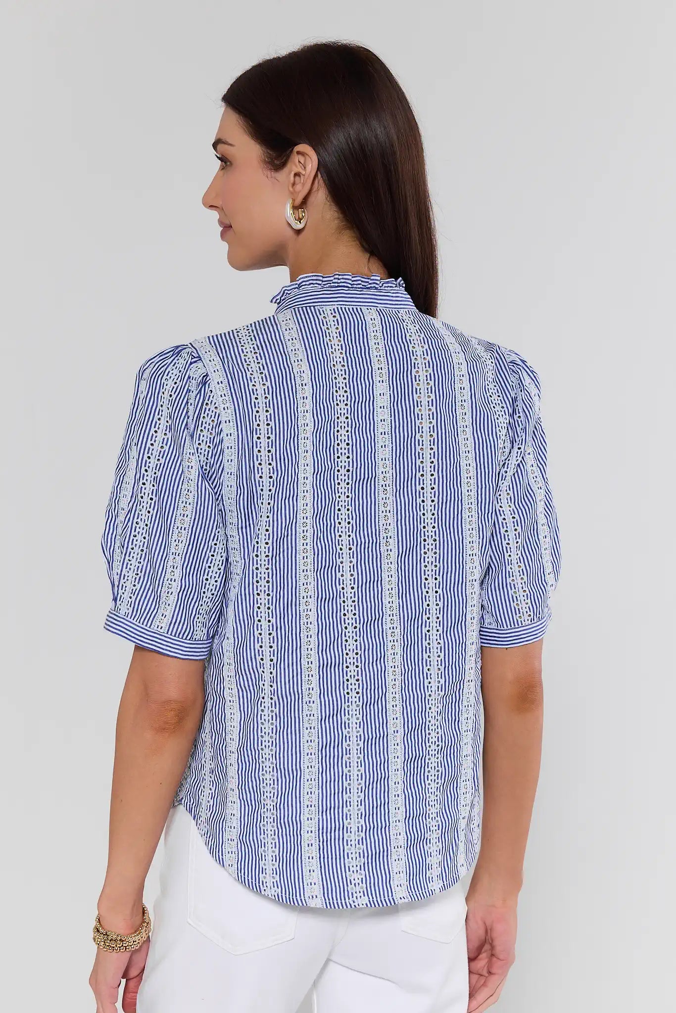Woman wearing a blue and white striped shirt against a plain background