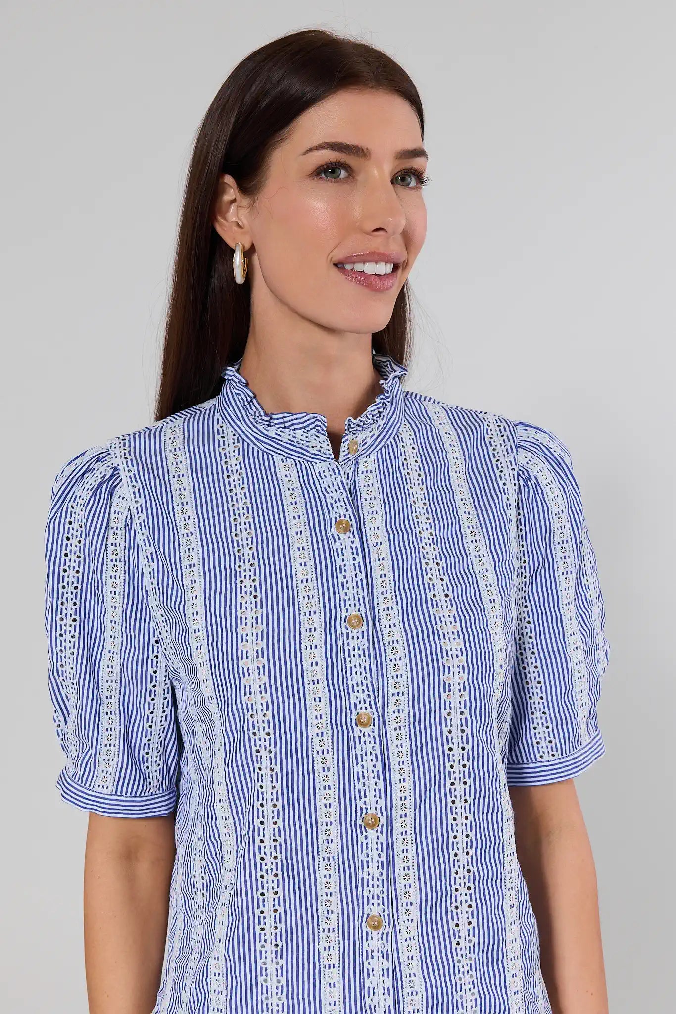 Woman wearing a blue and white striped dress with lace details on a gray background