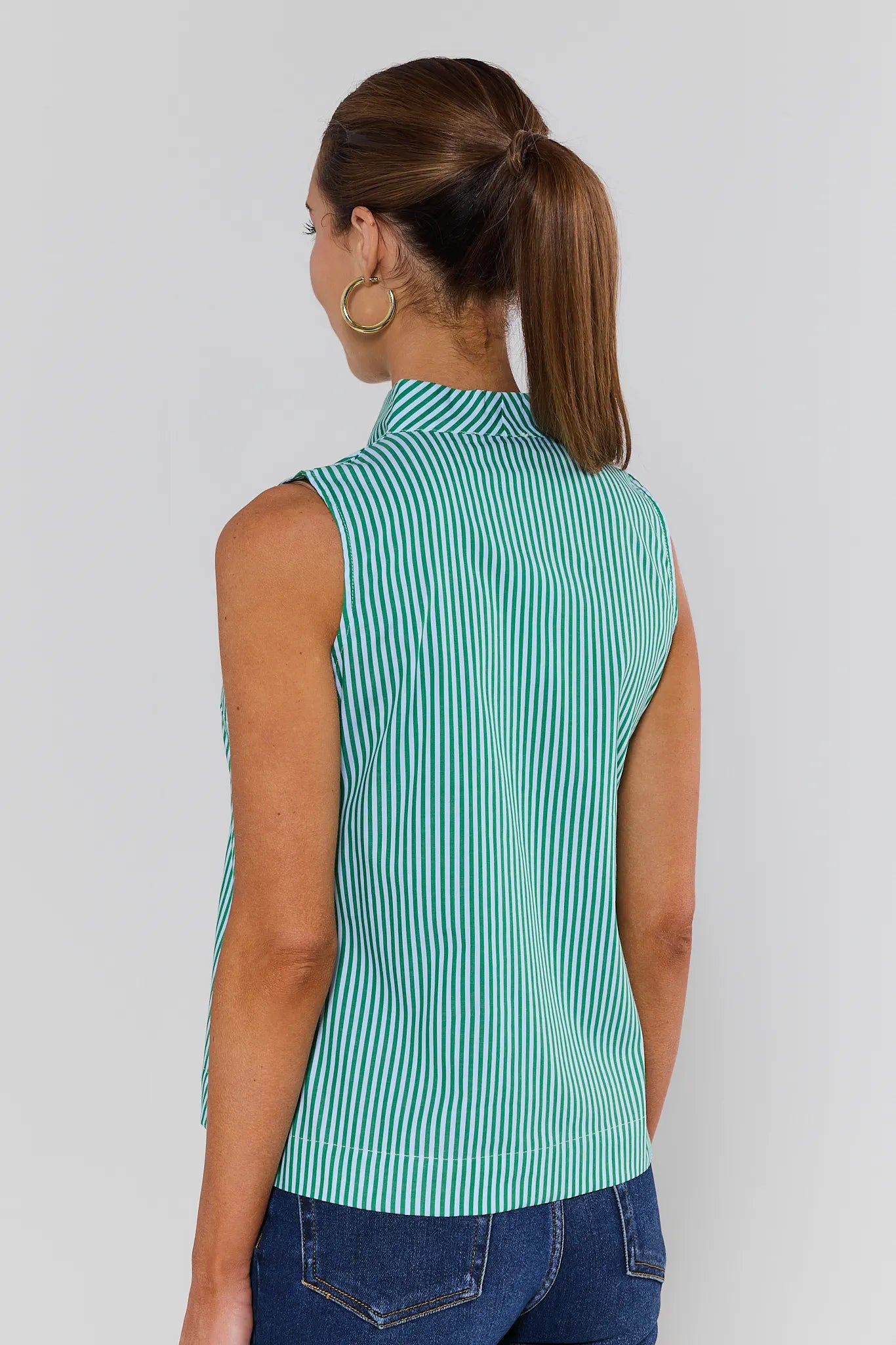 Woman wearing a green and white striped sleeveless shirt against a plain background