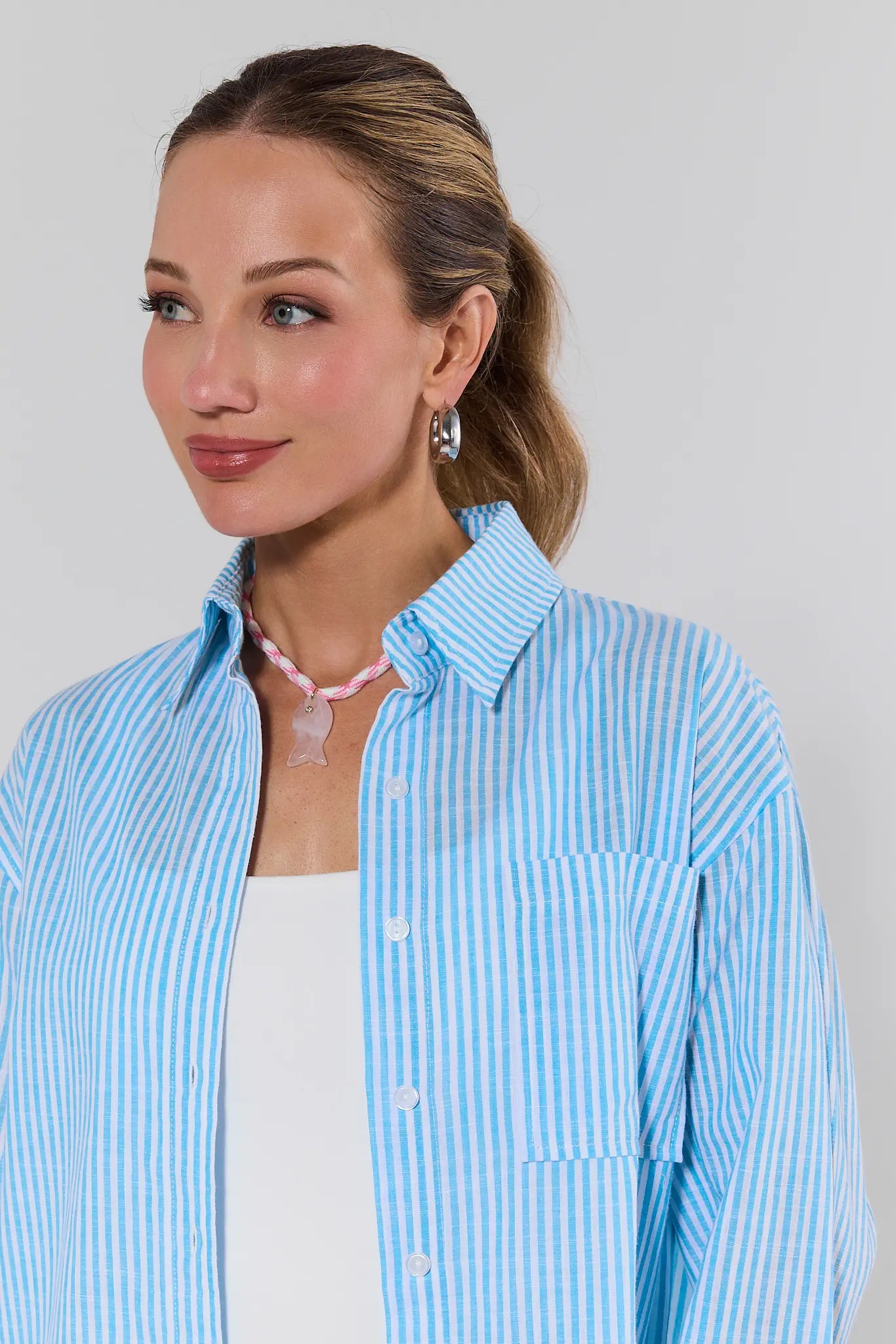 Woman wearing a light blue striped shirt against a plain background