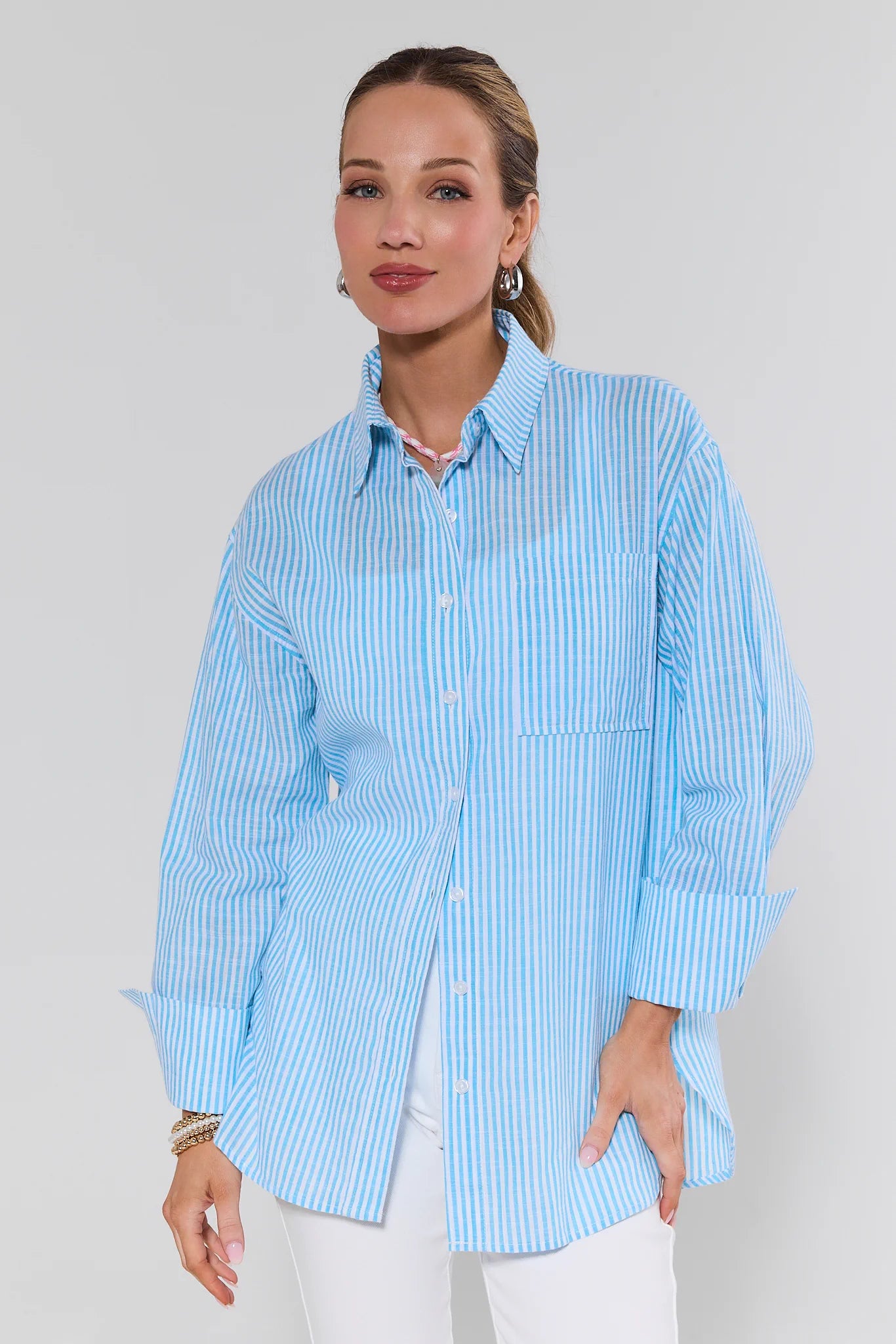Woman wearing a light blue striped shirt against a plain background
