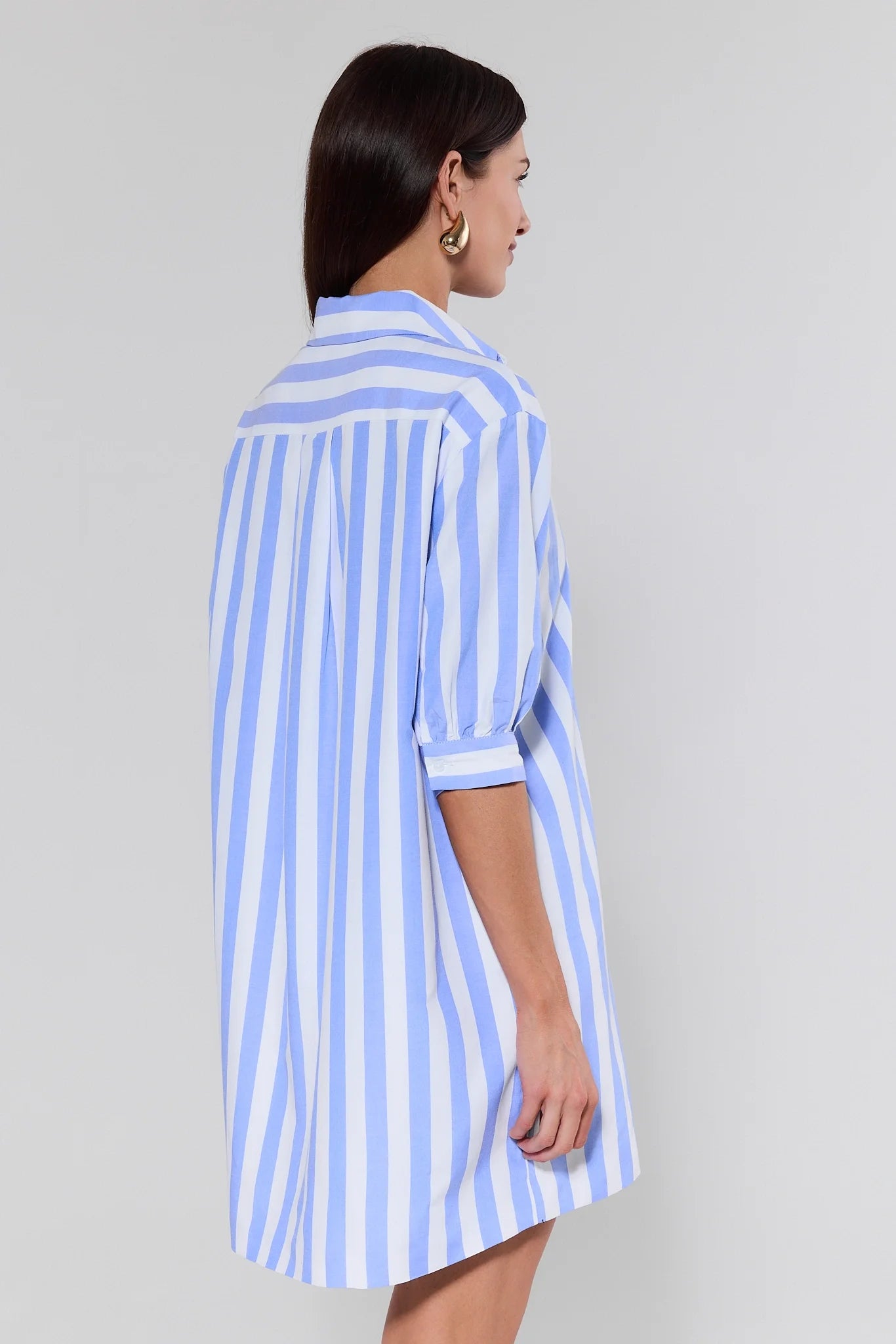 Woman wearing a blue and white striped dress against a gray background