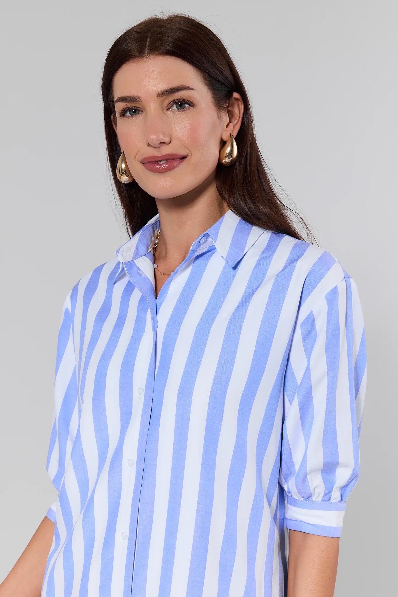 Woman wearing a blue and white striped shirt against a gray background