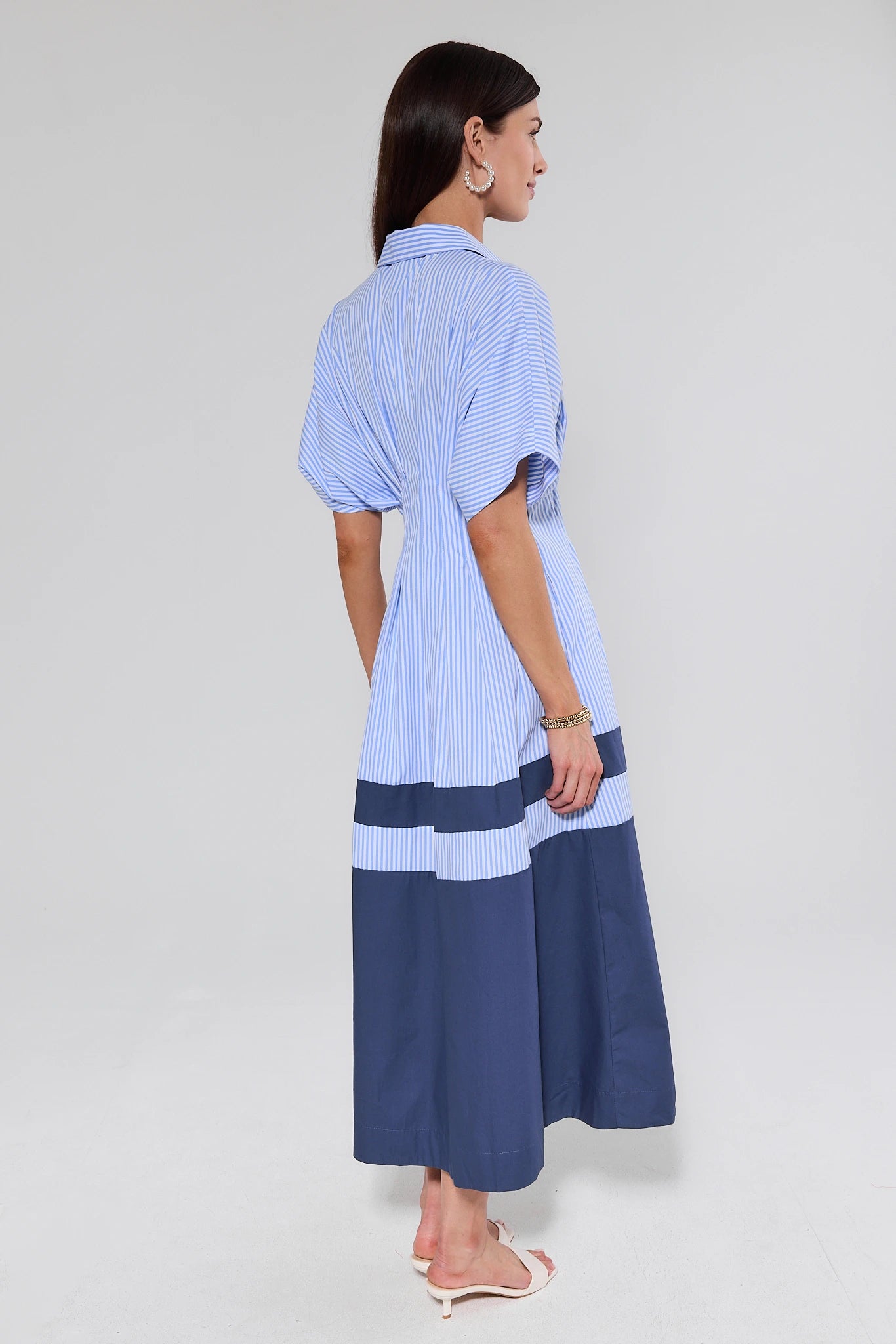 Woman wearing a blue and white striped dress on a light gray background