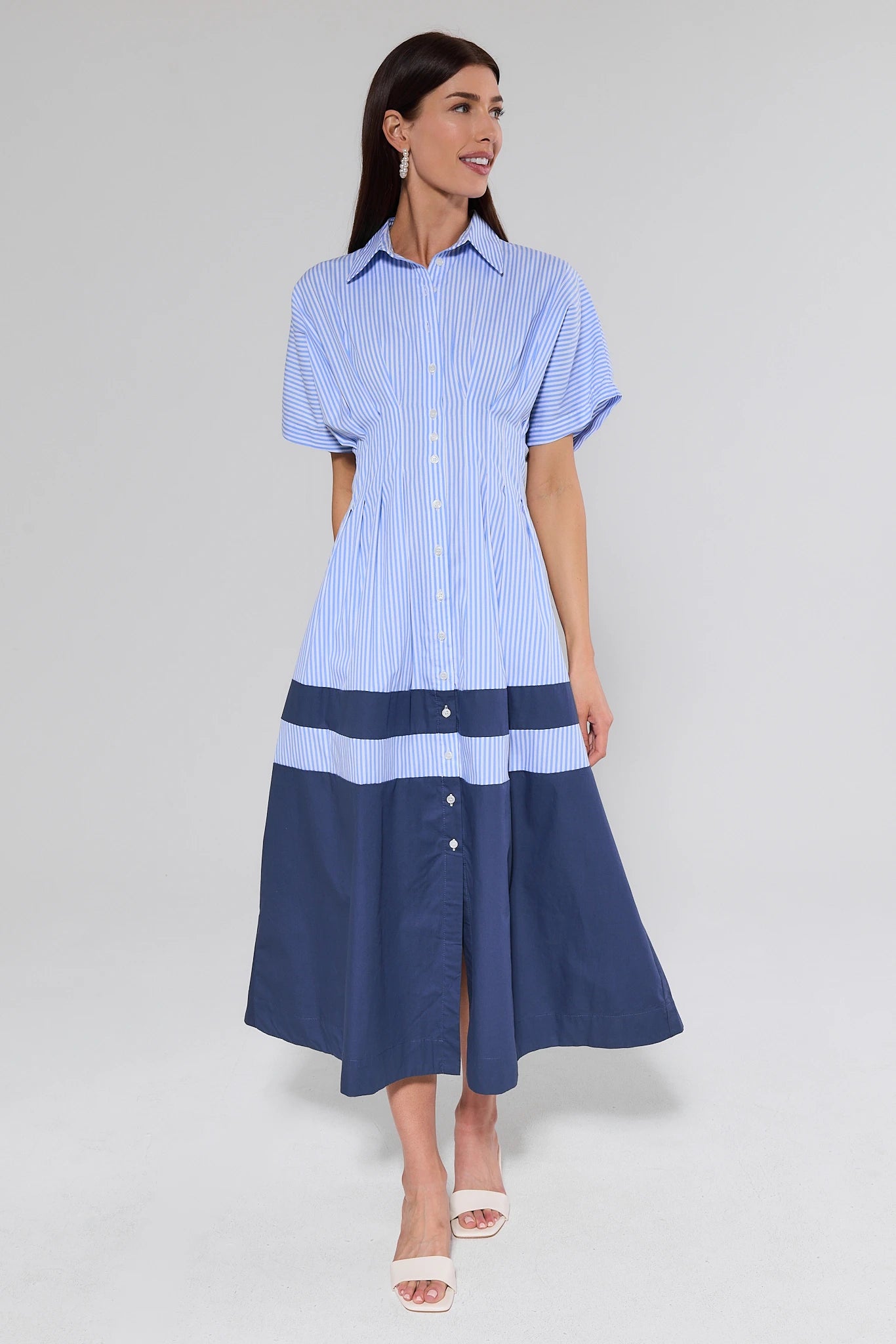Woman wearing a blue and white striped dress on a gray background