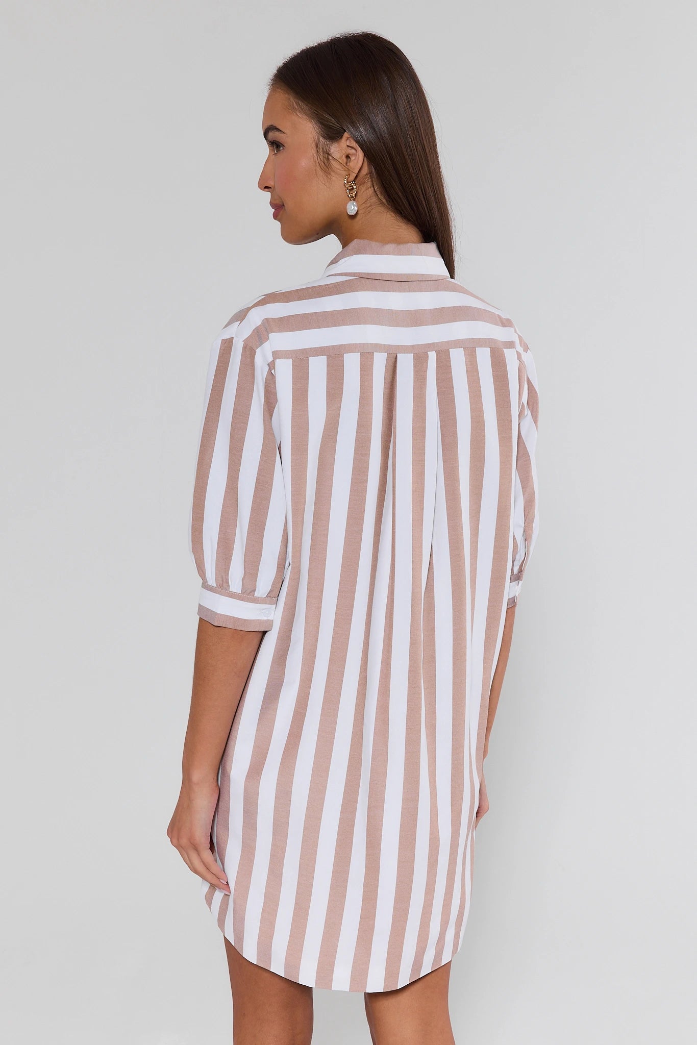 Woman wearing a striped shirt dress against a plain background