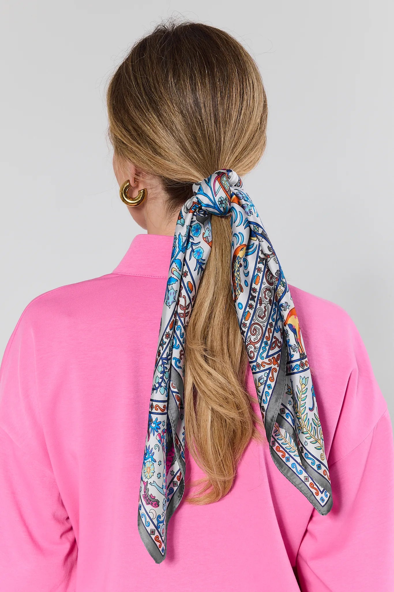 purple patterned scarf tied in hair on white background