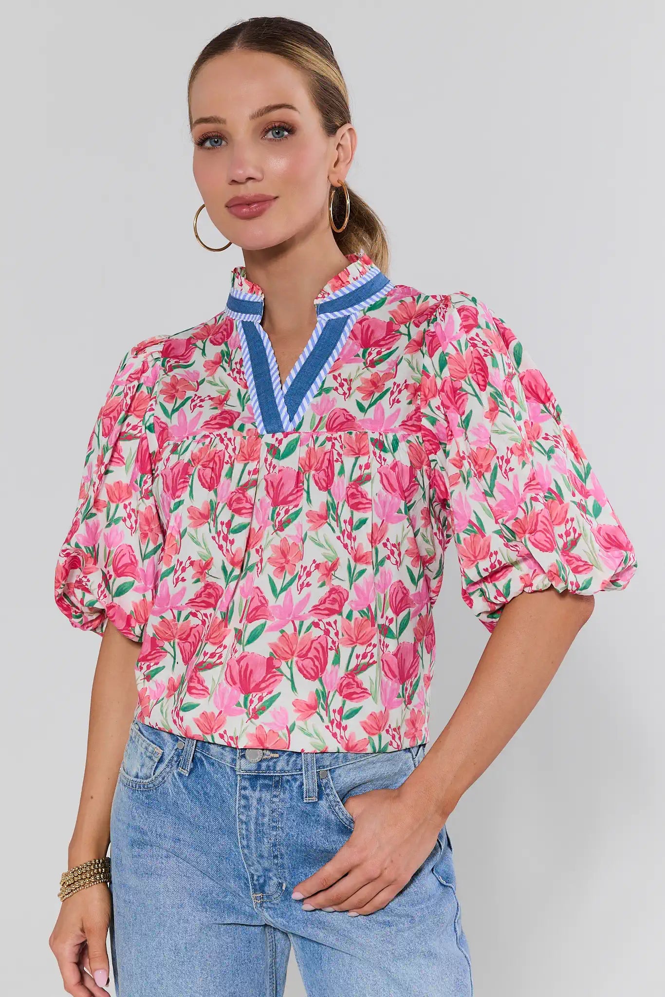 Woman wearing a pink floral blouse with blue accents on a background