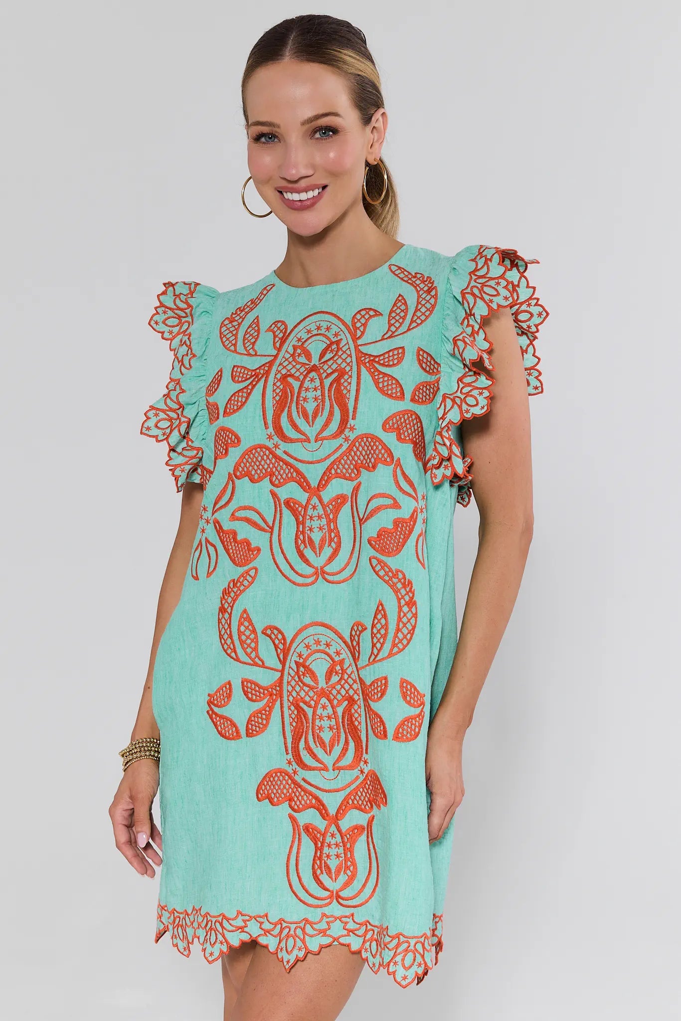 Woman wearing a turquoise dress with red floral patterns on a white background
