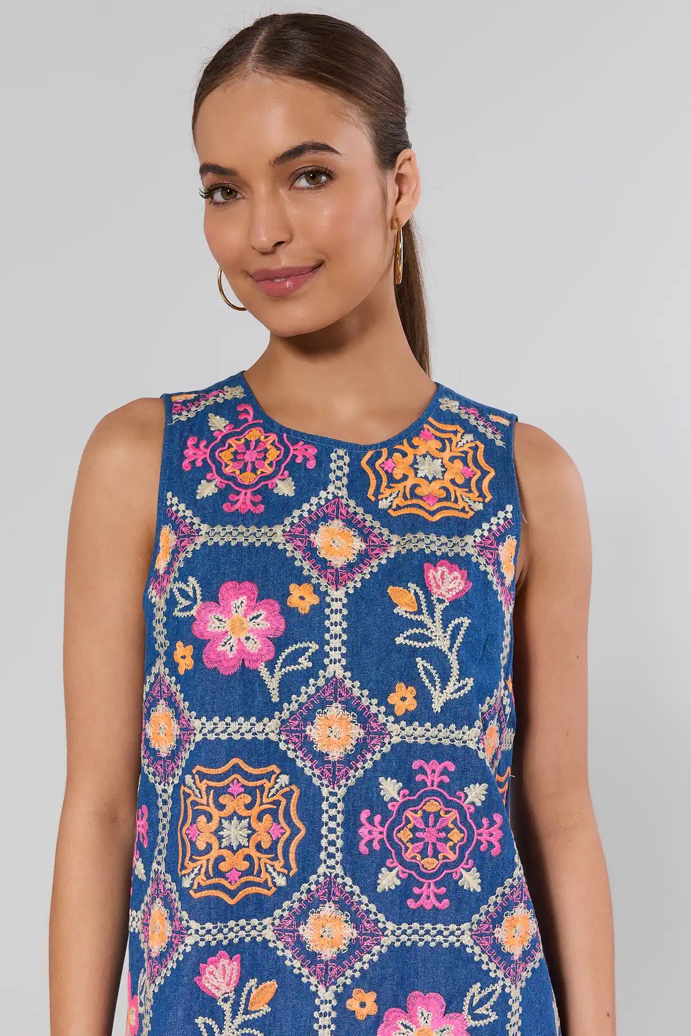 Woman wearing a blue sleeveless dress with colorful floral patterns on a gray background