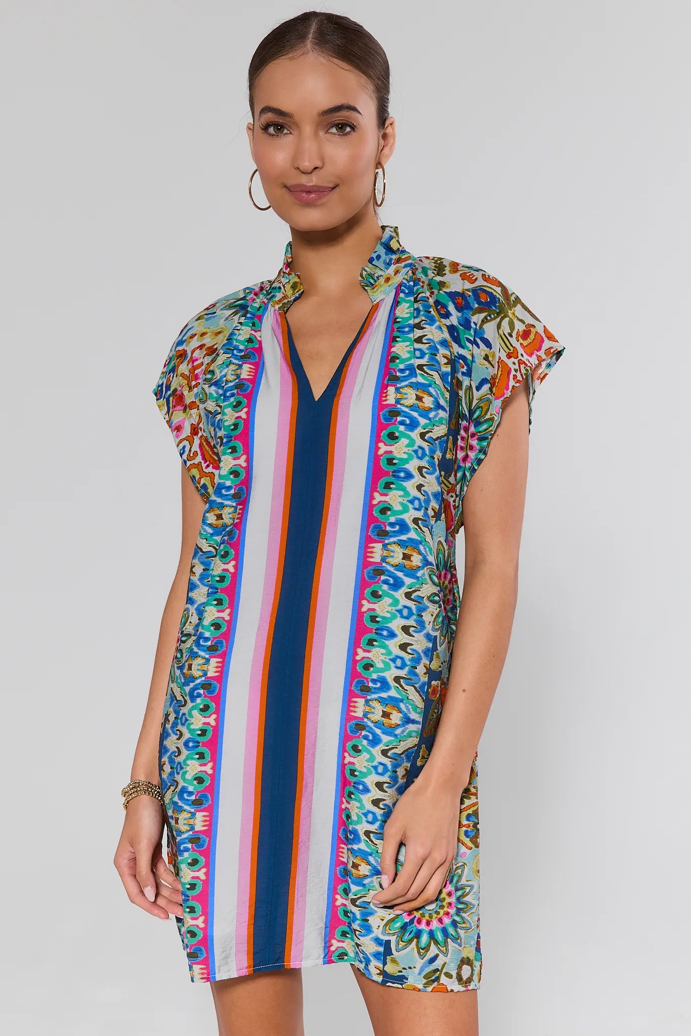 Woman wearing a colorful patterned dress on a plain background