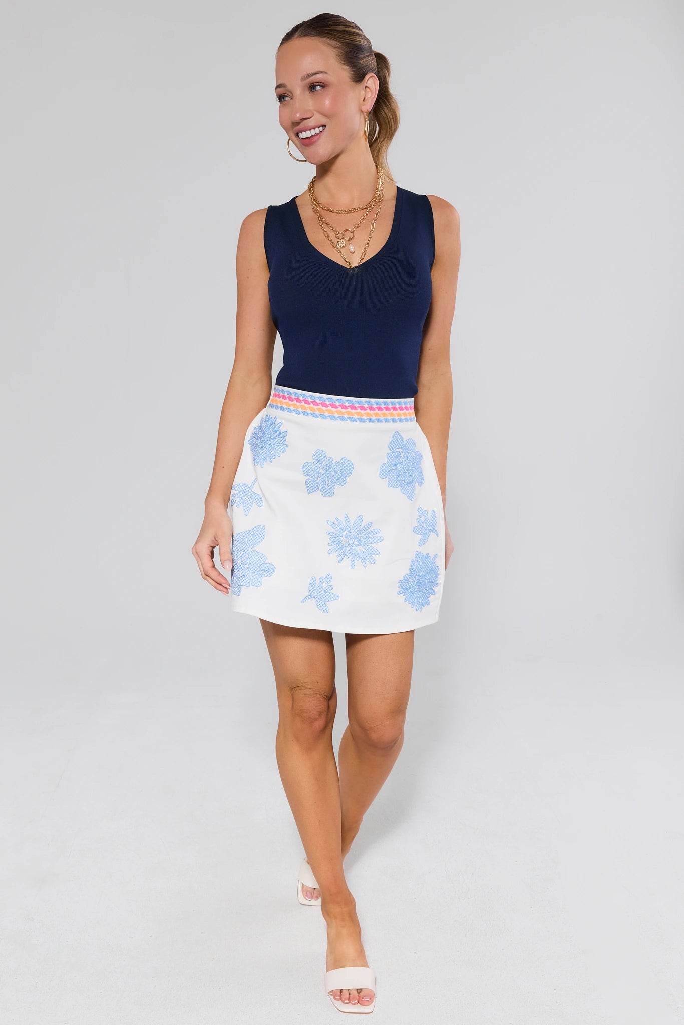 Woman wearing a navy top and light blue floral skirt on a gray background