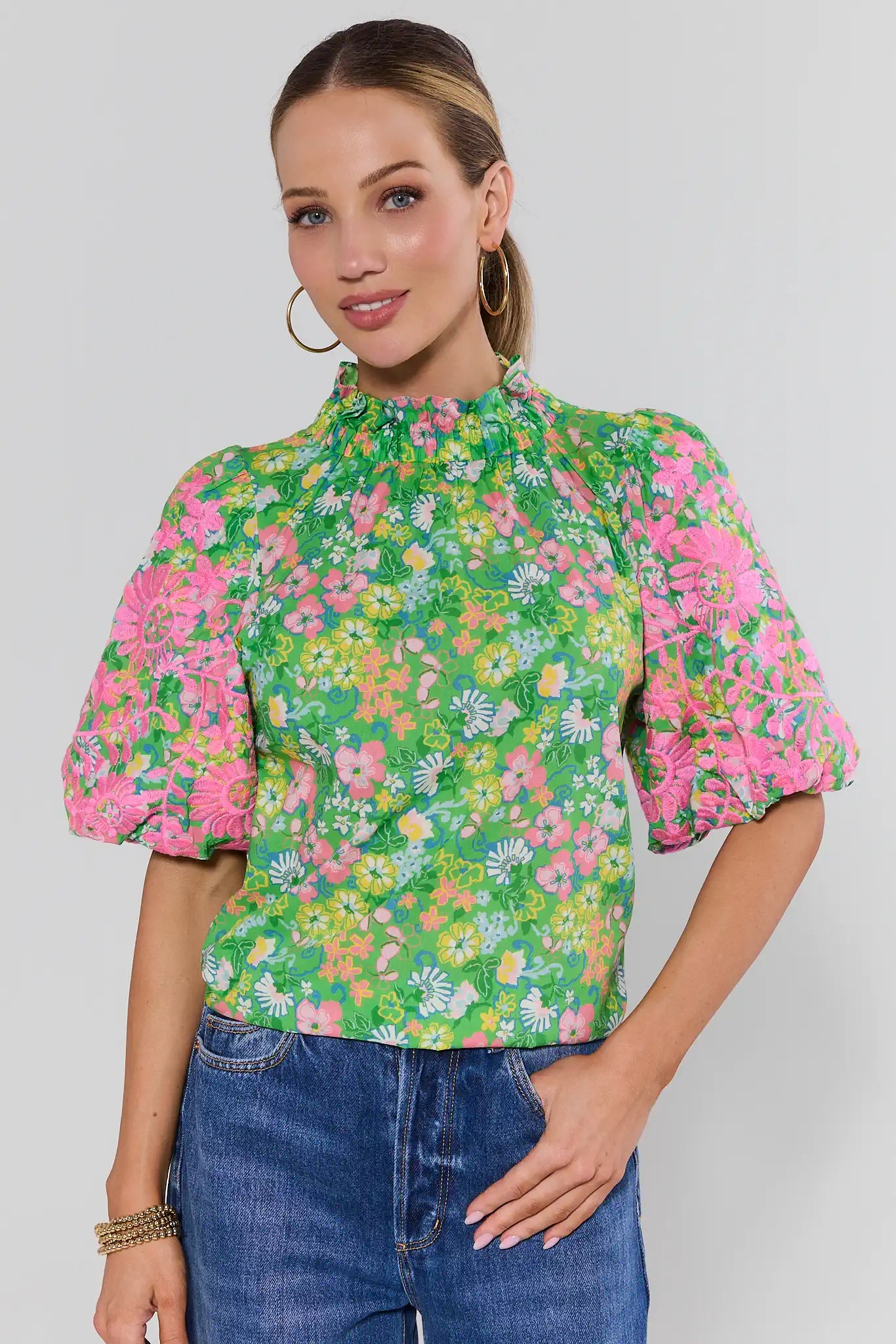 Woman wearing a floral blouse with puffed sleeves on a plain background