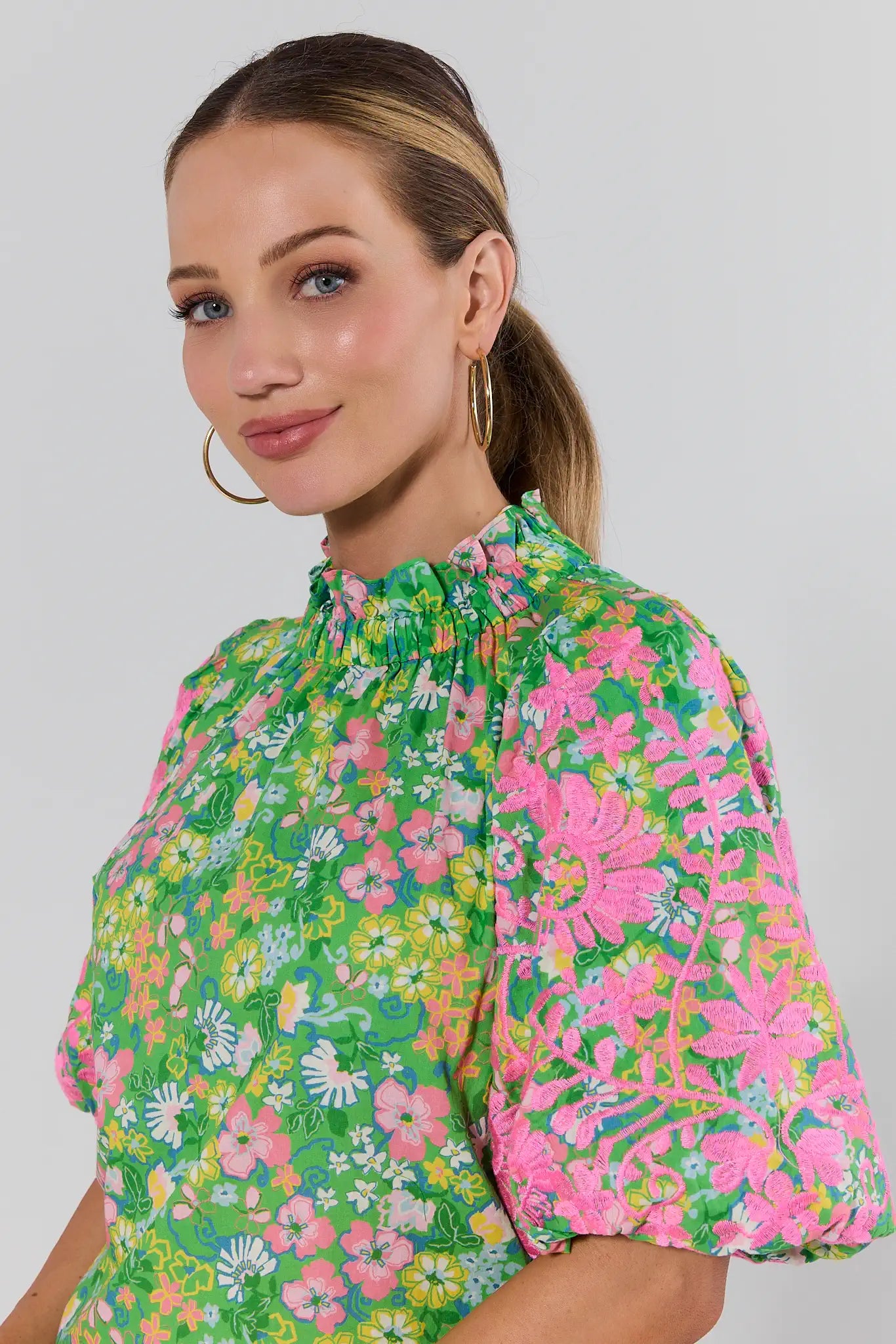 Woman wearing a colorful floral blouse against a plain background